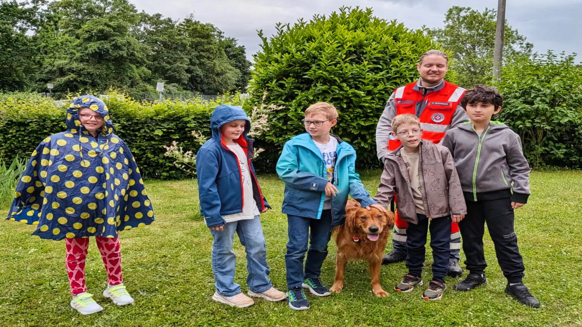 Gruppenbild mit 5 Schüler*innen und einem Erwachsenen in einer Uniform. Vor der Gruppe steht ein Hund.
