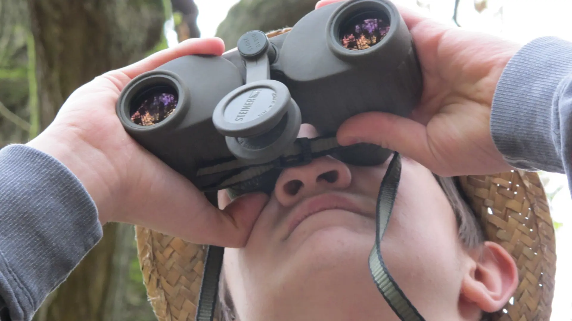 Ein junger Mann schaut durch ein Fernglas.