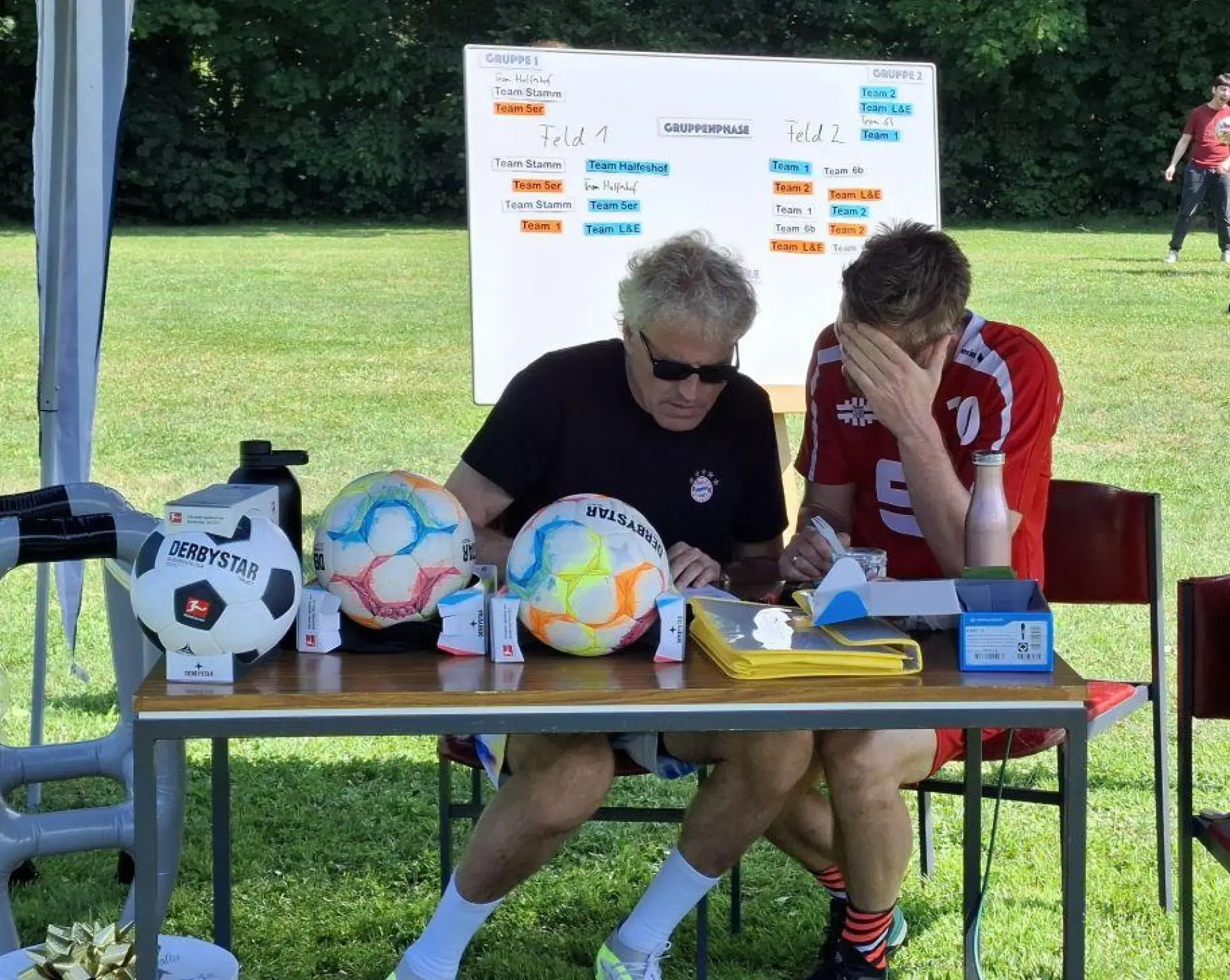 Schiedsrichter diskutieren am Tisch beim Fußball-Turnier