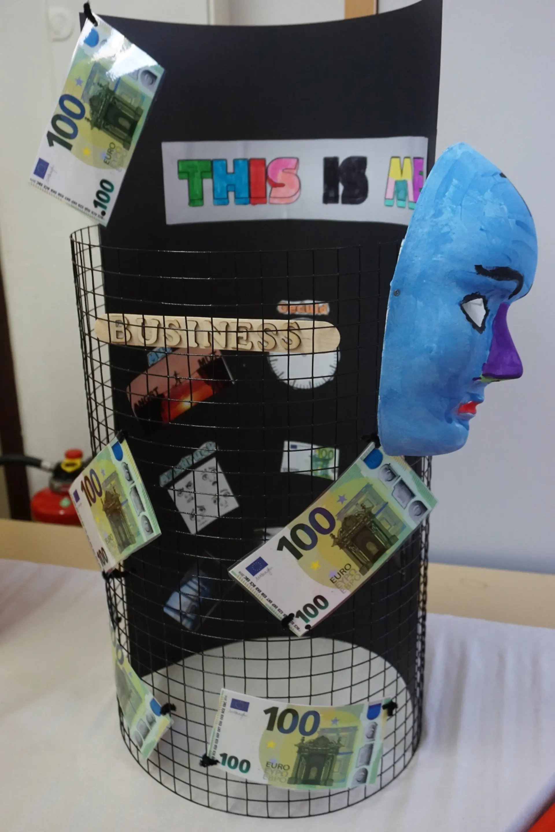 In der Projektwoche hergestelltes Projekt eines Schülers zur eigenen Darstellung für den Tag der offenen Tür in Form einer Säule mit Fotos und gruseliger Maske