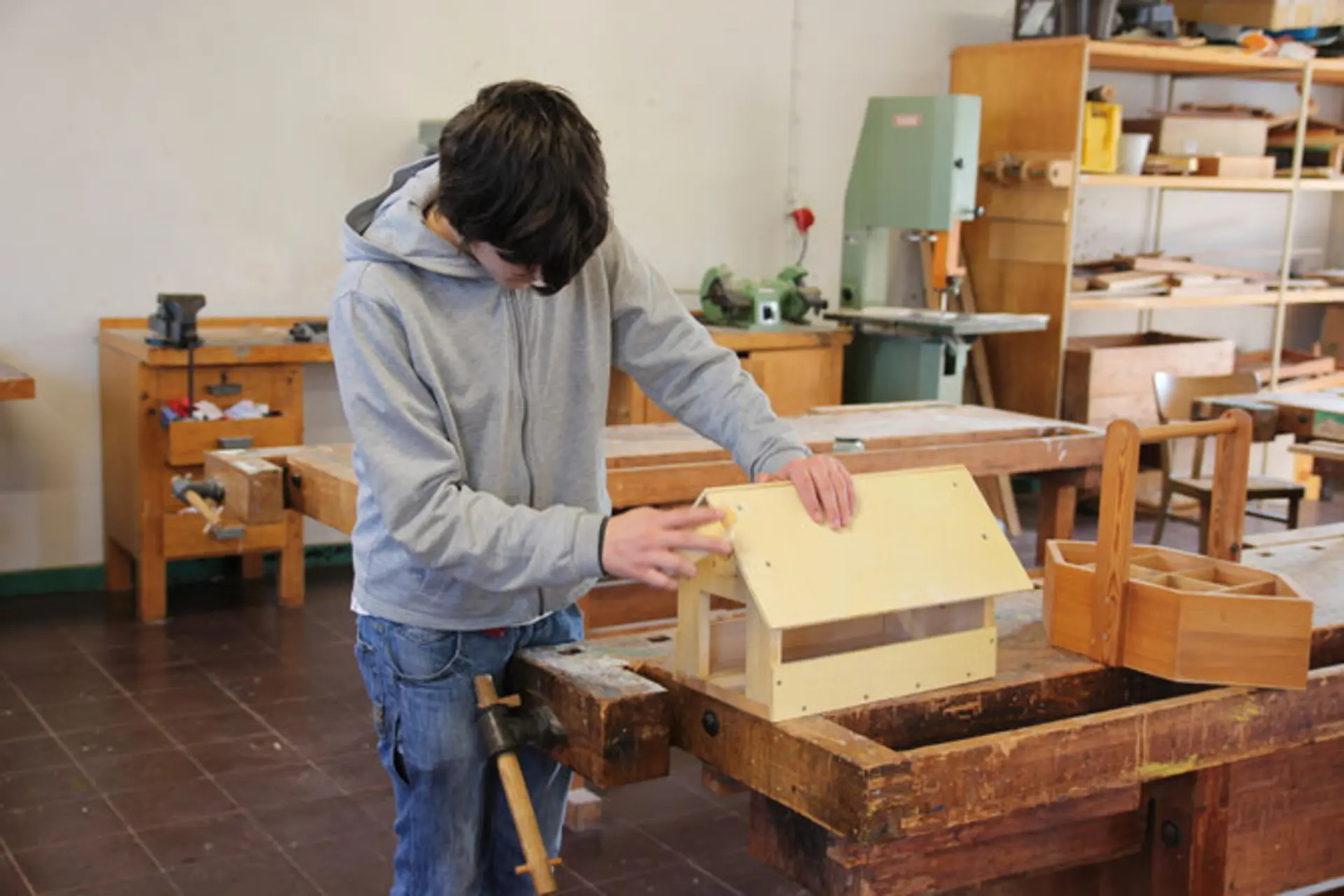 Ein Schüler der Werkstattklasse Holz baut ein Vogelhaus