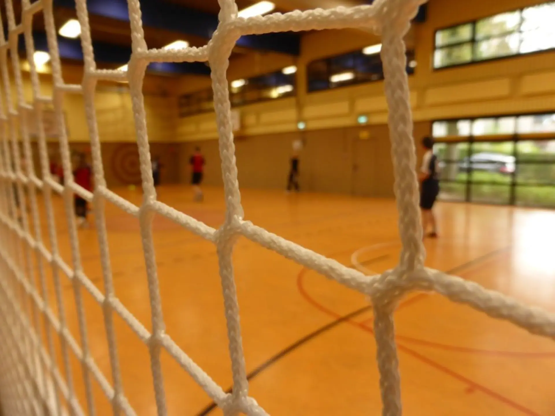 Blick in eine Turnhalle durch die Maschen eines Fußballtornetzes