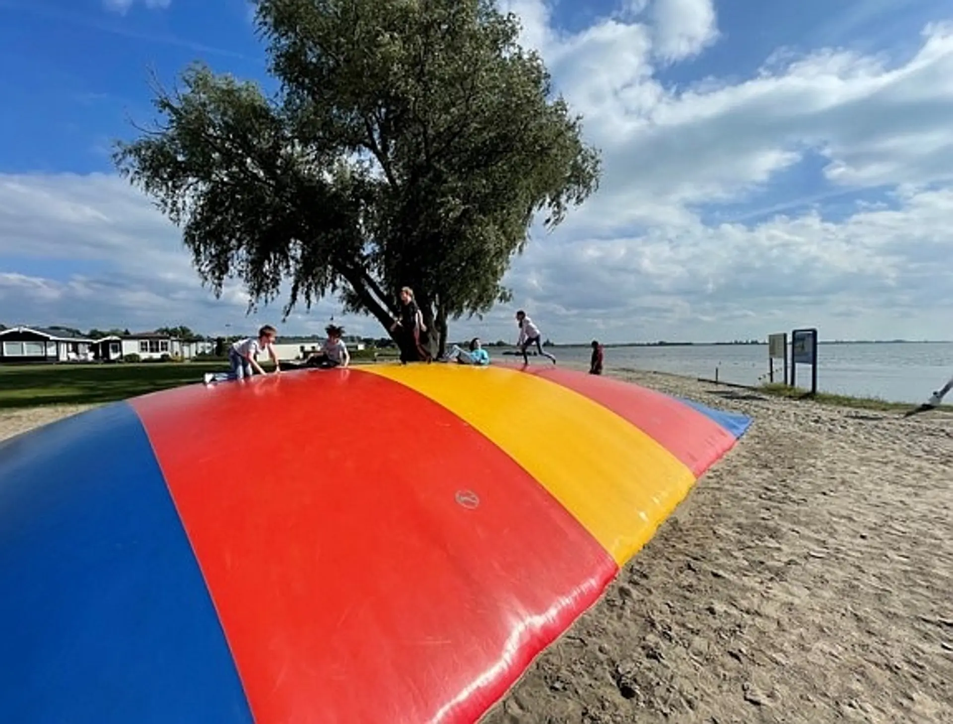Kinder auf einem riesigen Hüpfkissen am Strand