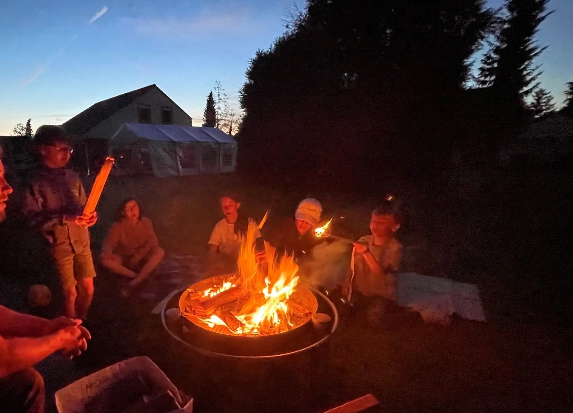 Mehrere Personen sitzen an einem Lagerfeuer