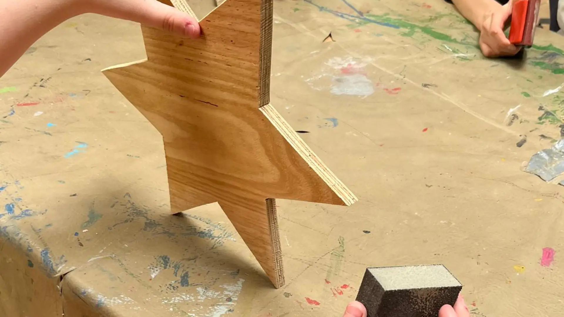 Klassenraum mit Arbeitsmaterial in Regalen und auf Werkbänken. Von der Decke hängen Vierfachsteckdosen. Im Hintergrund eine Standbohrmaschine.