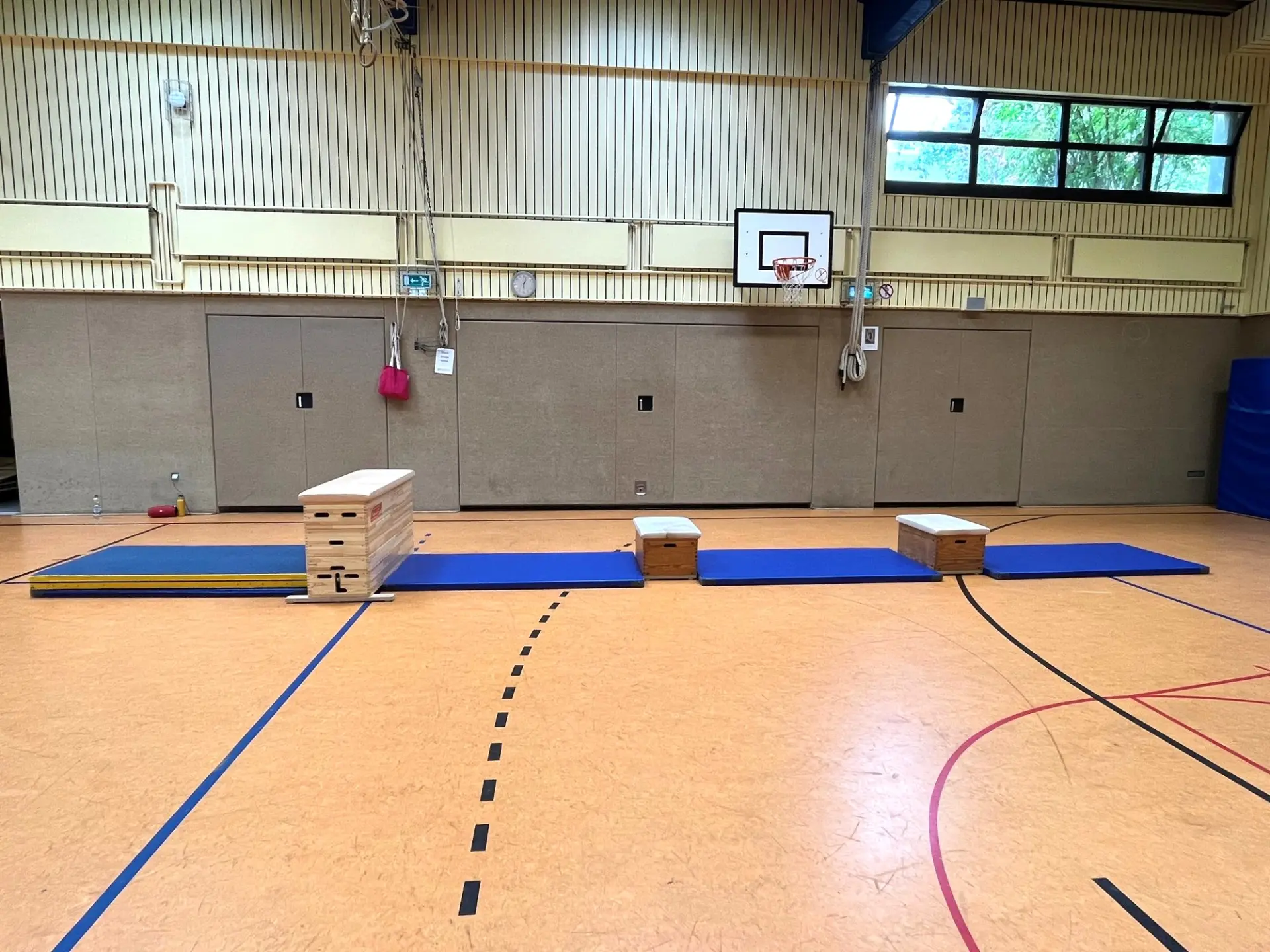 Blick in eine Schul-Turnhalle: im Vordergrund ein Aufbau aus Kästen und Matten
