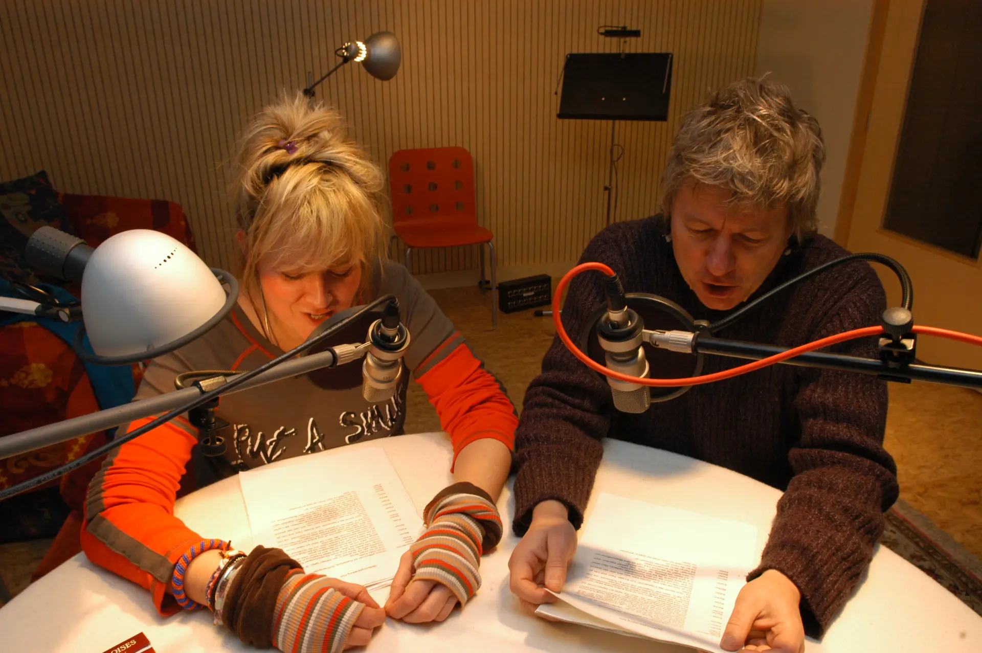 Foto: Zwei Personen sprechen in einem Tonstudio Texte für einen Audioguide in Mikrofone ein.