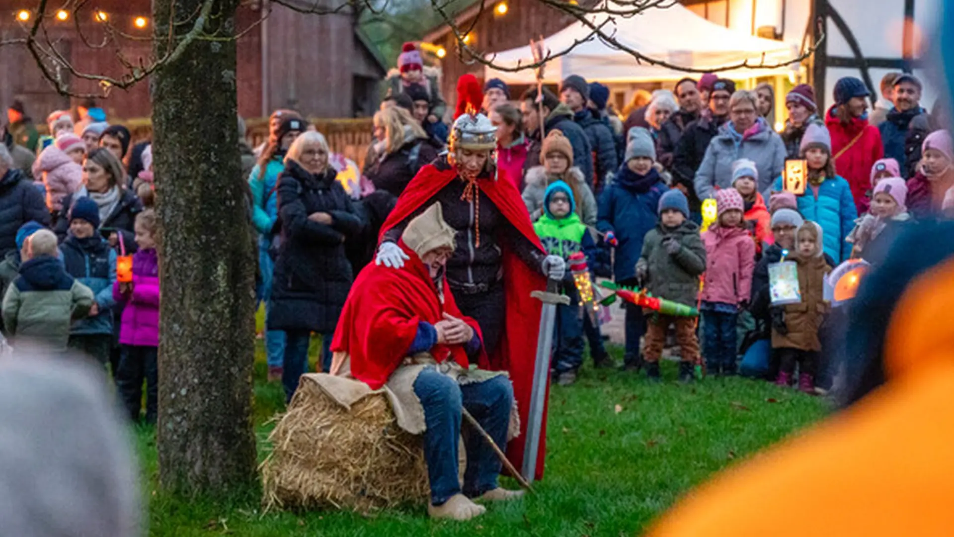  Kinder und Eltern sehen der Vorführung beim Martinsumzug zu. St. Martin beugt sich über den Bettler.
