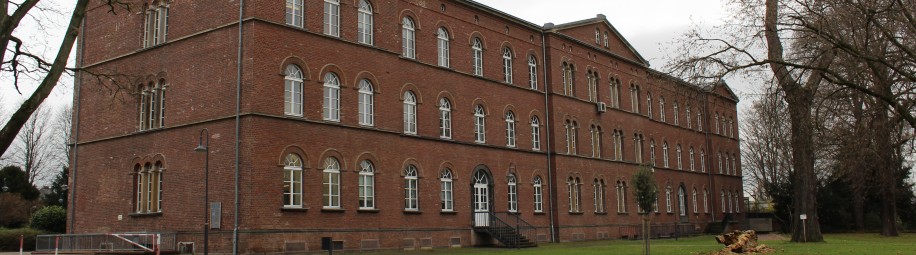 Rotes Backsteingeb&auml;ude mit 3 Giebeln in einem Park
