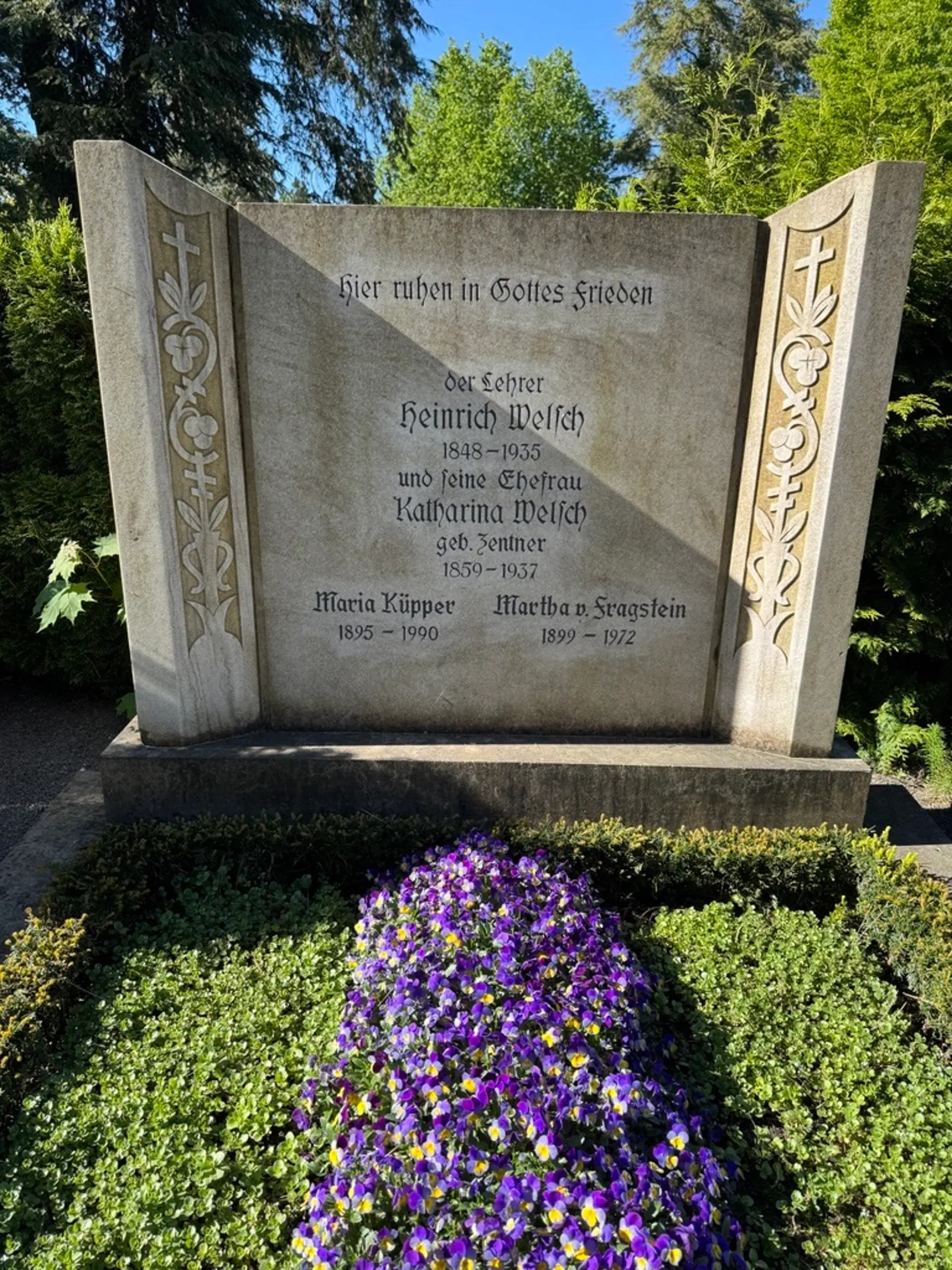 Das historische Grabmal von Heinrich Welsch (1848–1935) auf einem Friedhof in Köln-Kalk. Die Grabplatte trägt seinen Namen und seine Lebensdaten und ist von einer gepflegten Bepflanzung umgeben.