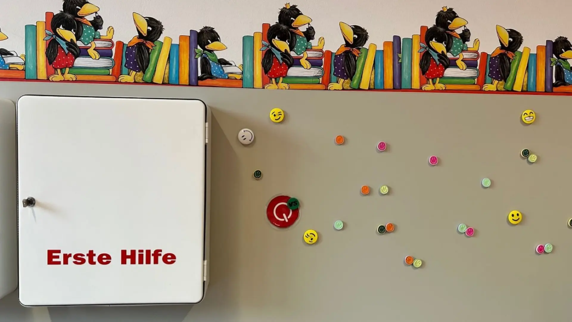 Erste Hilfe-Kasten an der Wand mit bunten Magneten daneben