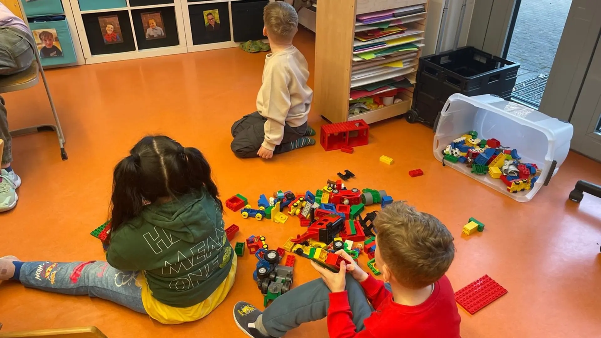 Kinder sitzen auf dem Boden und spielen mit Duplosteinen