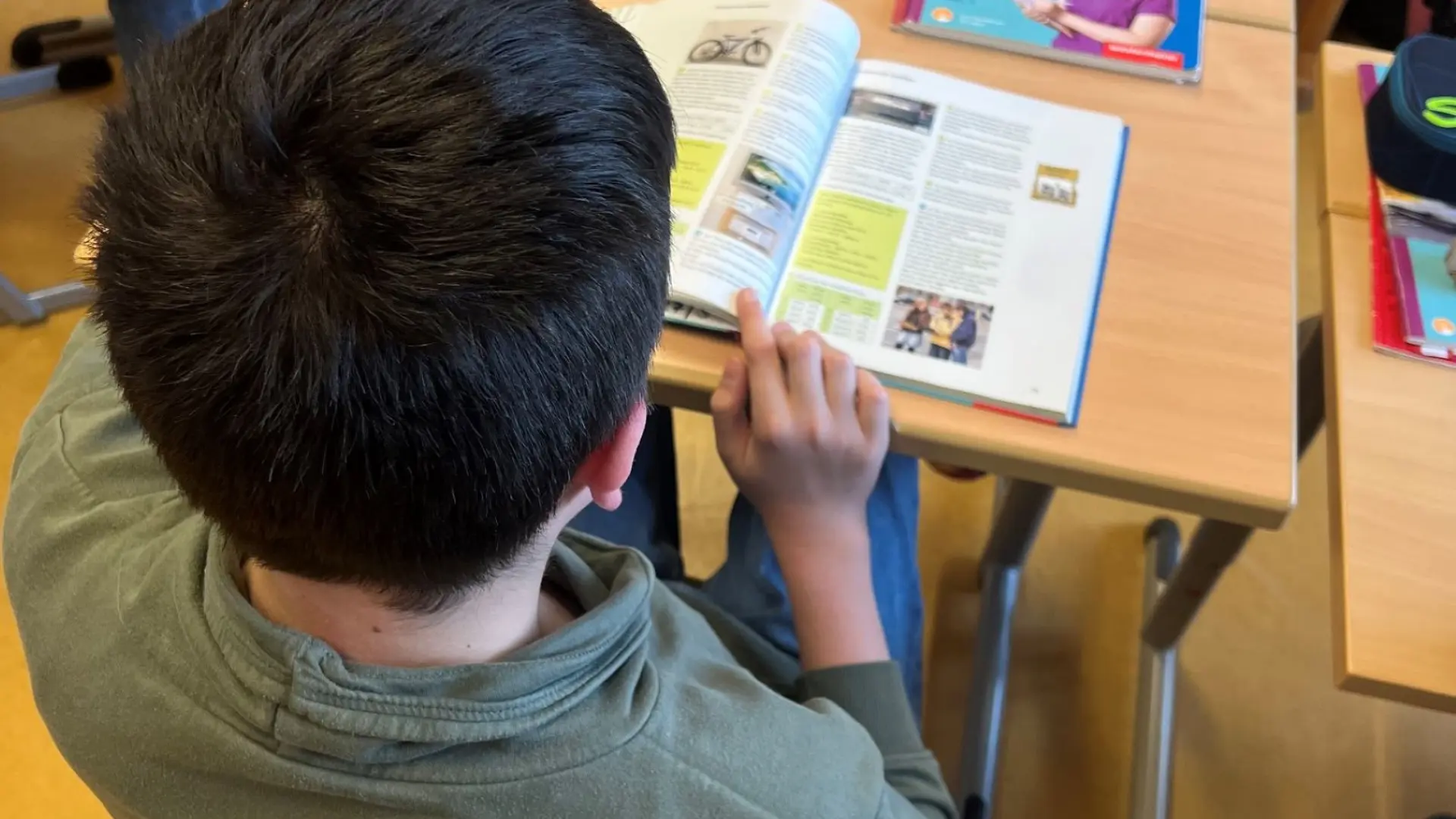 Kind liest im Klassenzimmer in einem Schulbuch