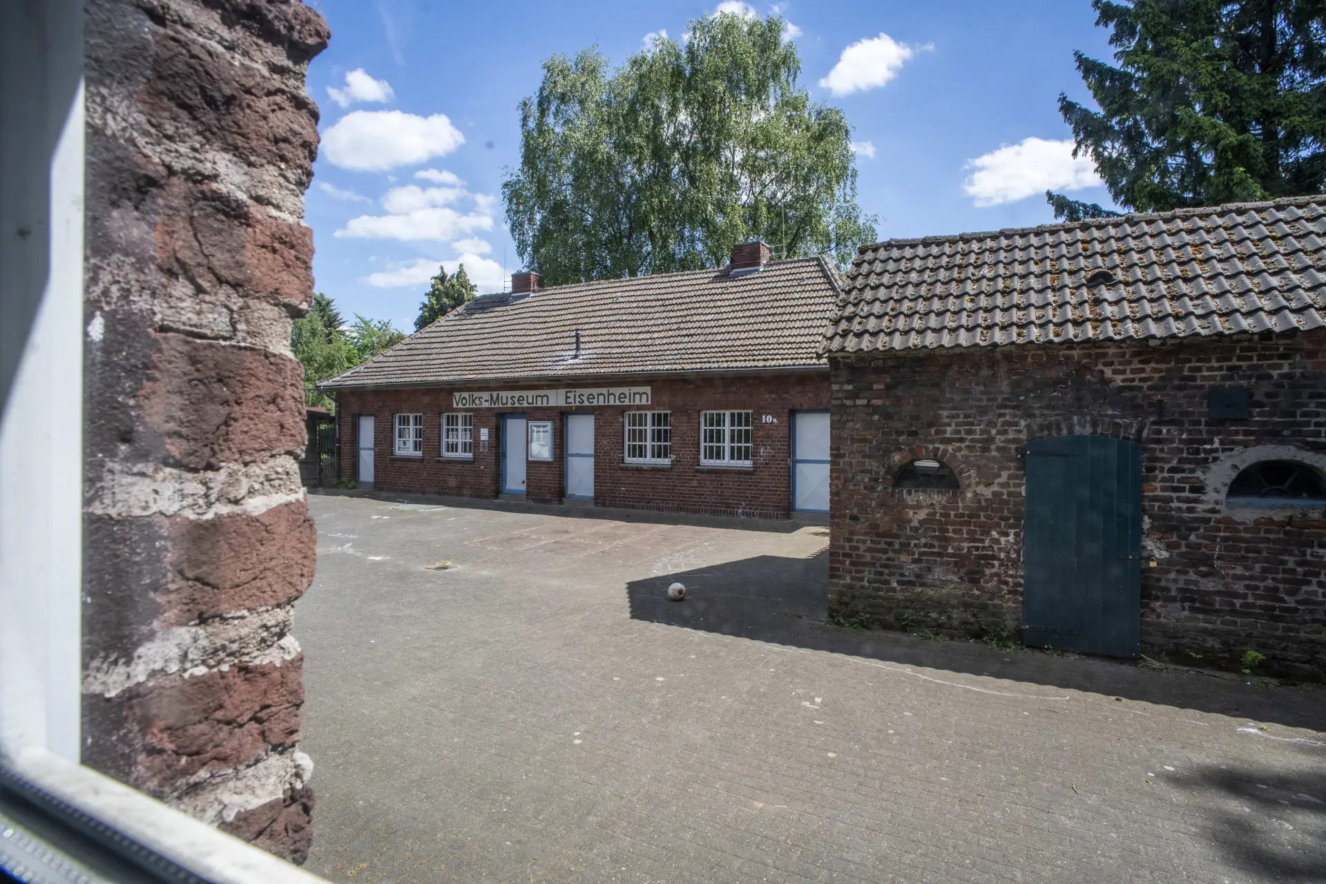 Außenansicht eines Hofs mit mehreren Backsteingebäuden und der Aufschrift "Volks-Museum Eisenheim"