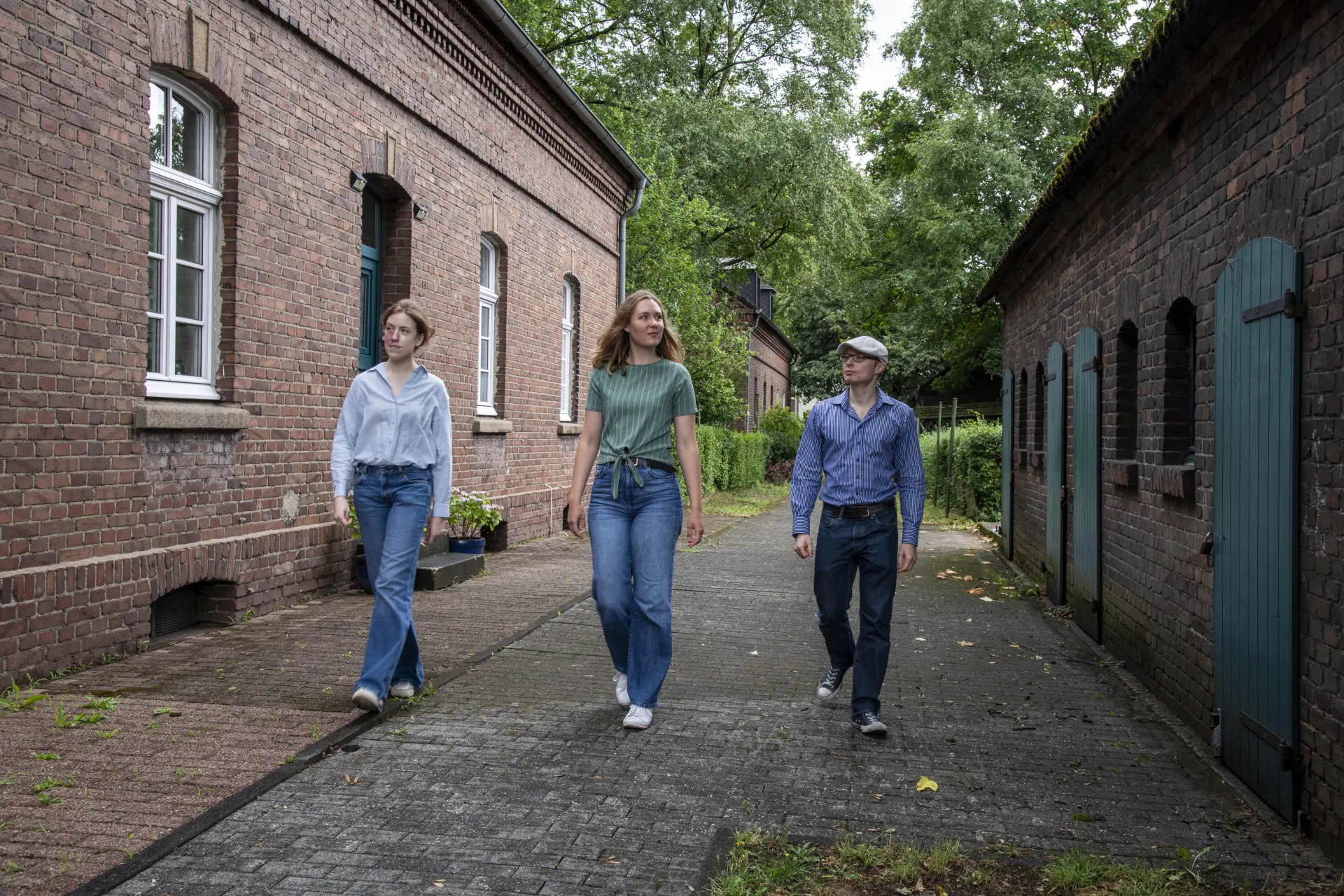 Zwei Frauen und ein Mann laufen nebeneinander eine Straße entlang