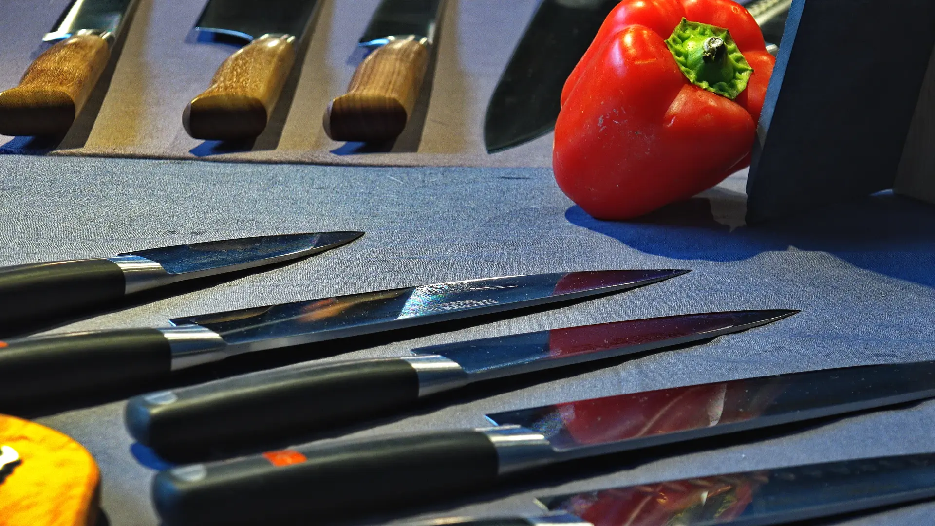 Schwarze Küchenmesser. Im Hintergrund liegt eine rote Paprika.