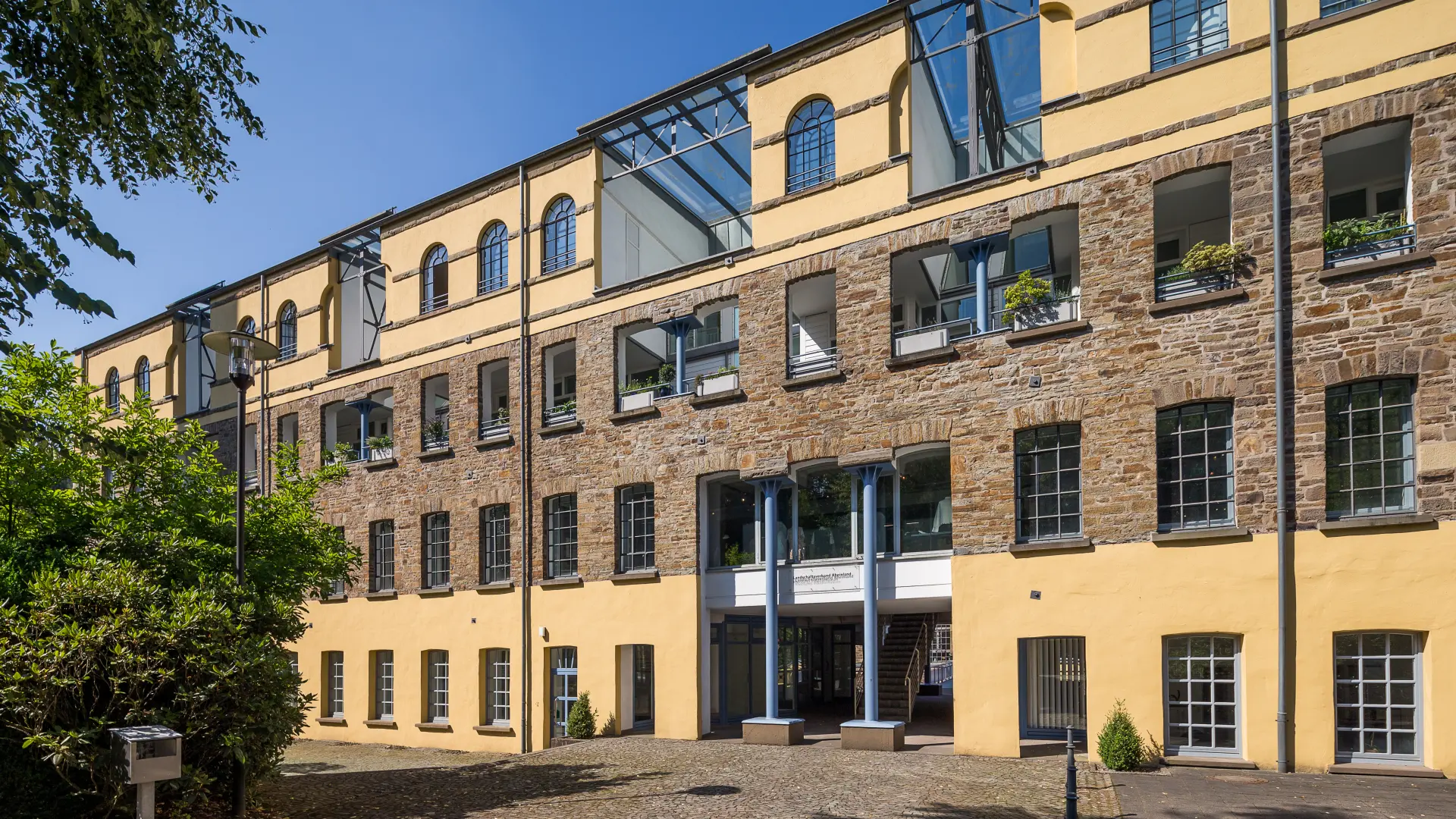 Ein Gebäude mit vielen Fenstern. Die Fassade ist teilweise aus Stein und teilweise gelb gestrichen.