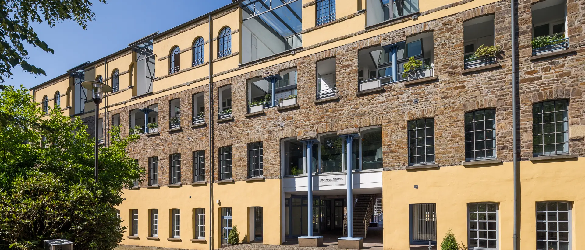 Ein Gebäude mit vielen Fenstern. Die Fassade ist teilweise aus Stein und teilweise gelb gestrichen.