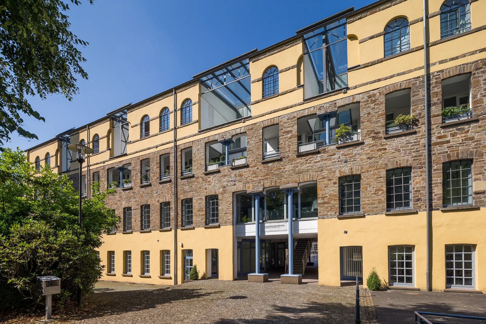Ein Gebäude mit vielen Fenstern. Die Fassade ist teilweise aus Stein und teilweise gelb gestrichen.