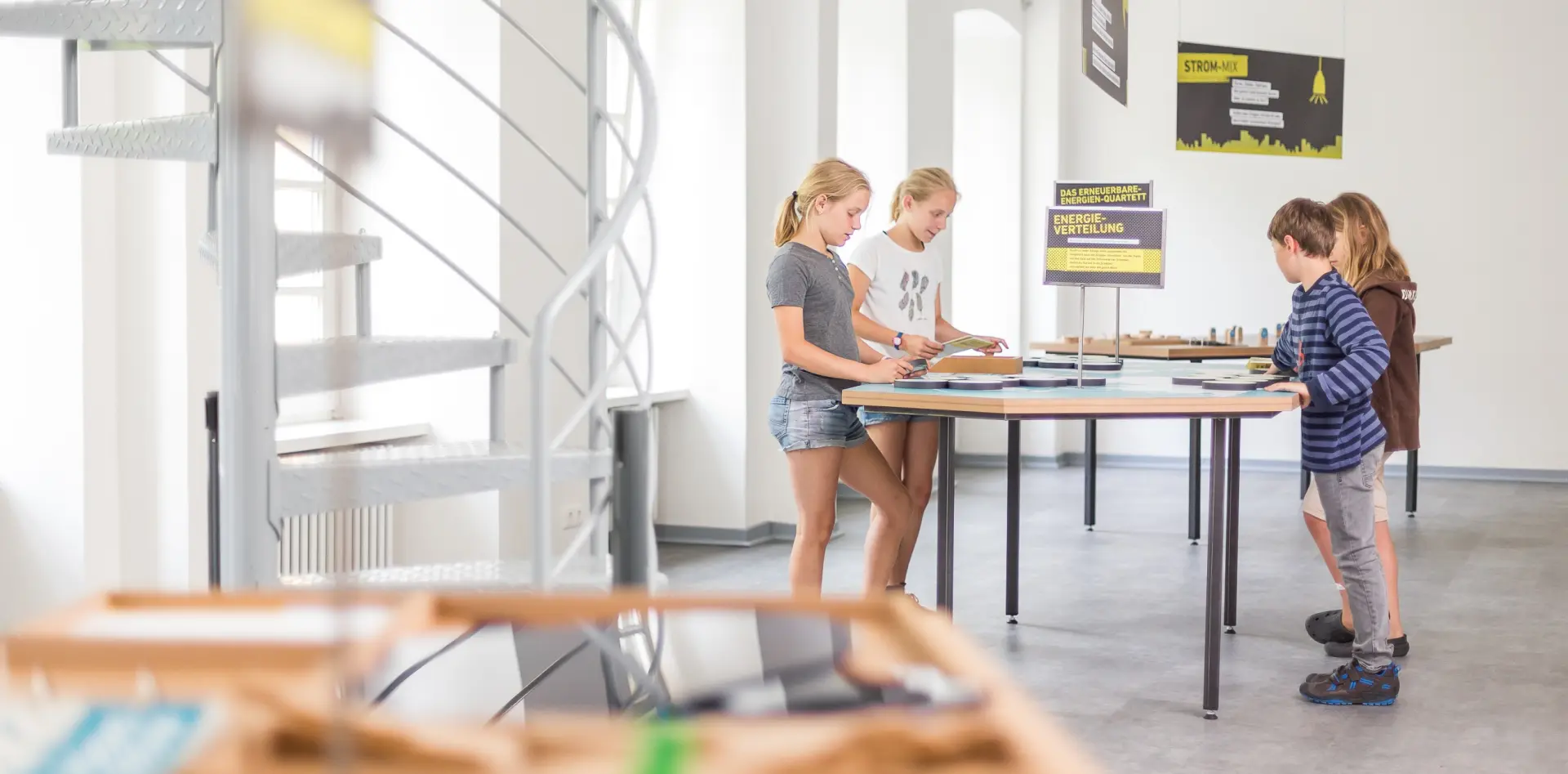 Vier Kinder arbeiten gemeinsam im Stehen an einem Arbeitstisch.