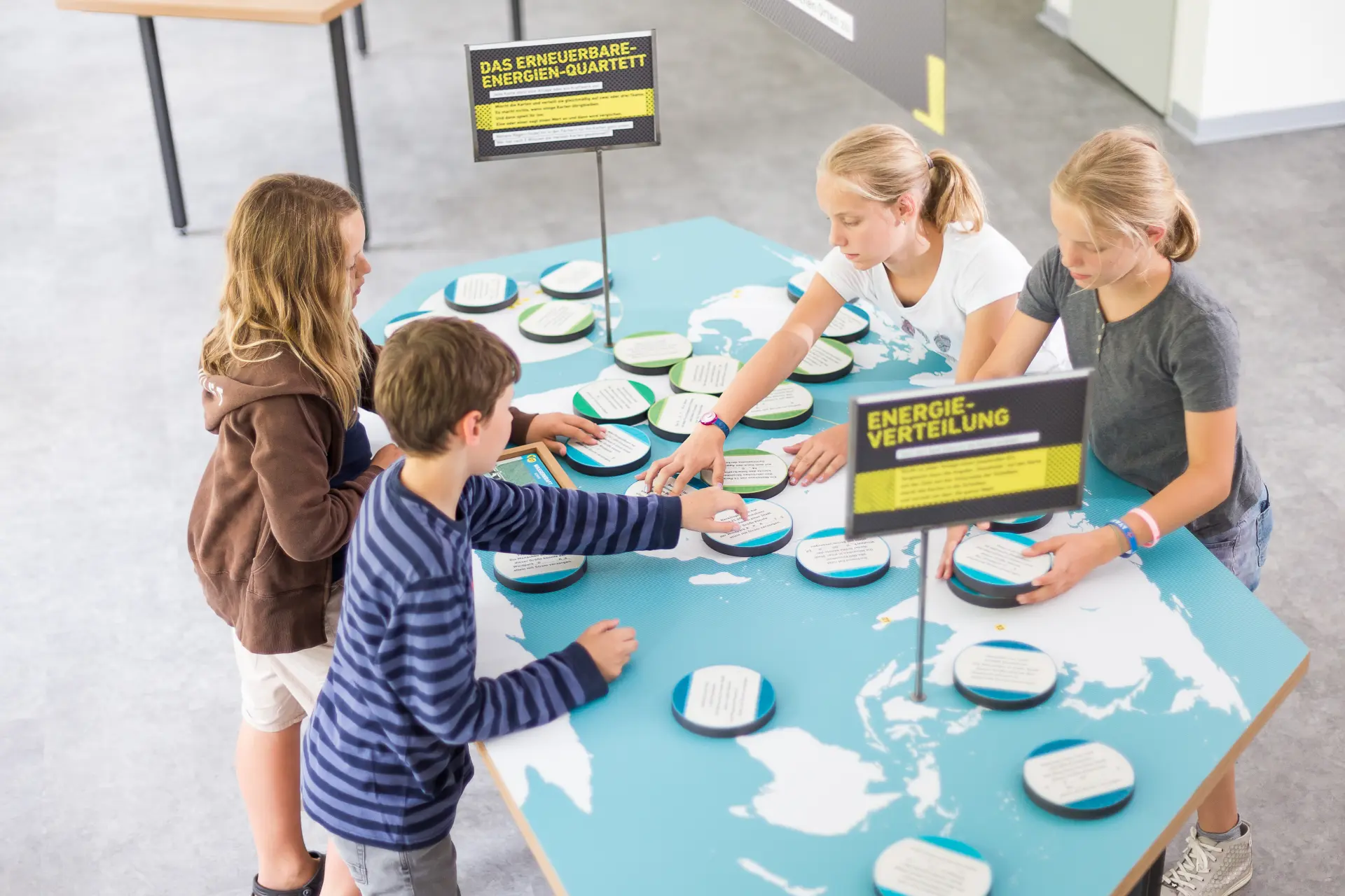 Vier Kinder an einem Arbeitstisch von schräg oben.