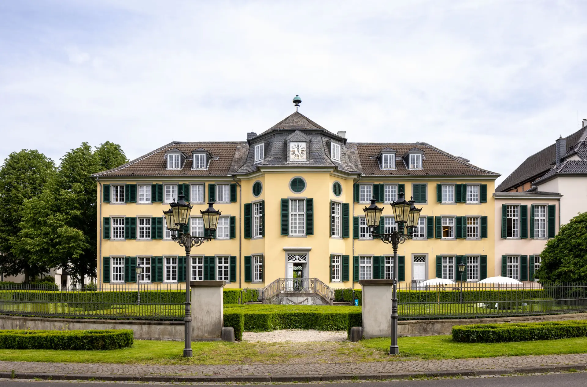 Ein gelbes barockes Herrenhaus mit grünen Fensterläden.