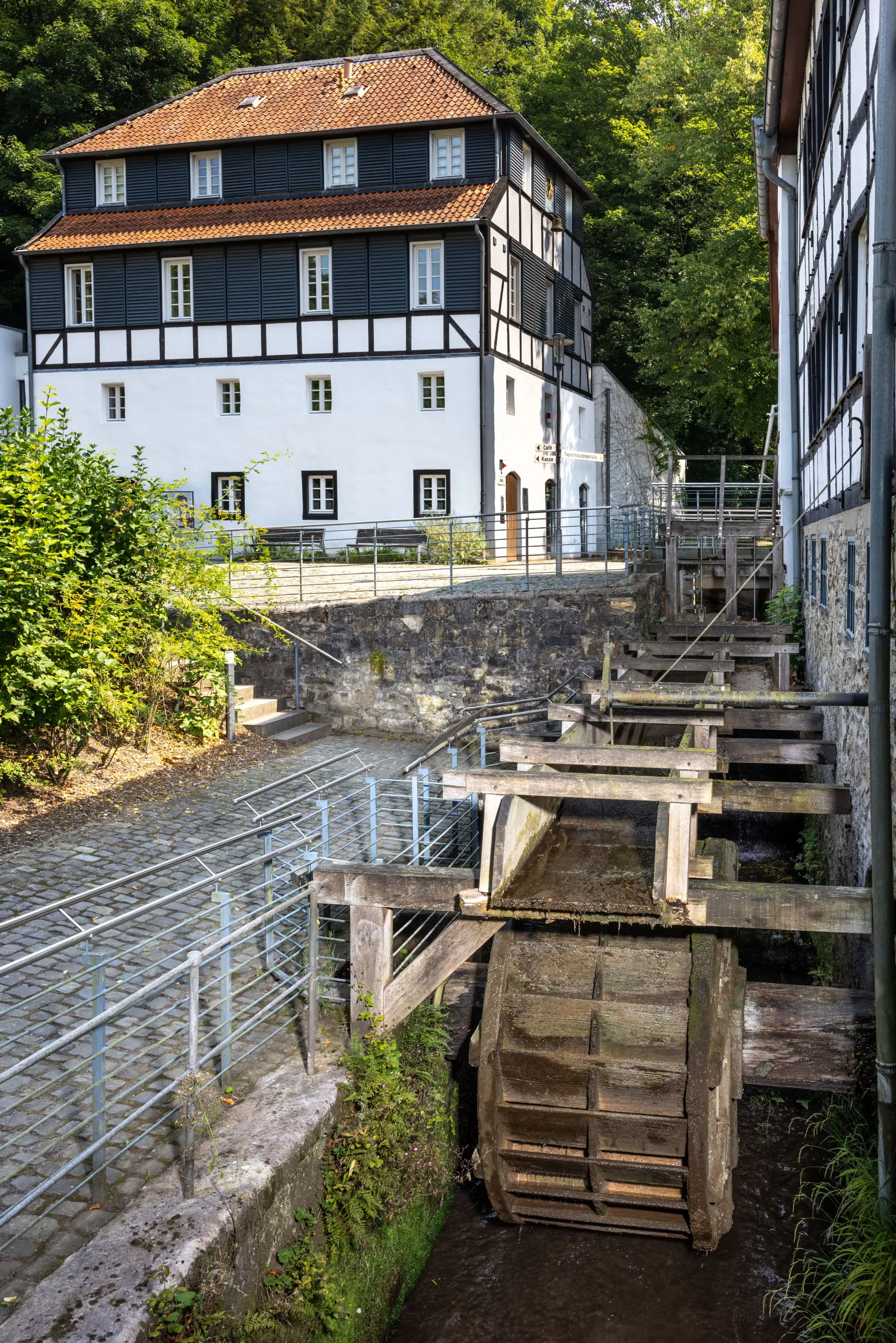 Hölzernes Mühlrad, im Hintergrund Fachwerkensemble