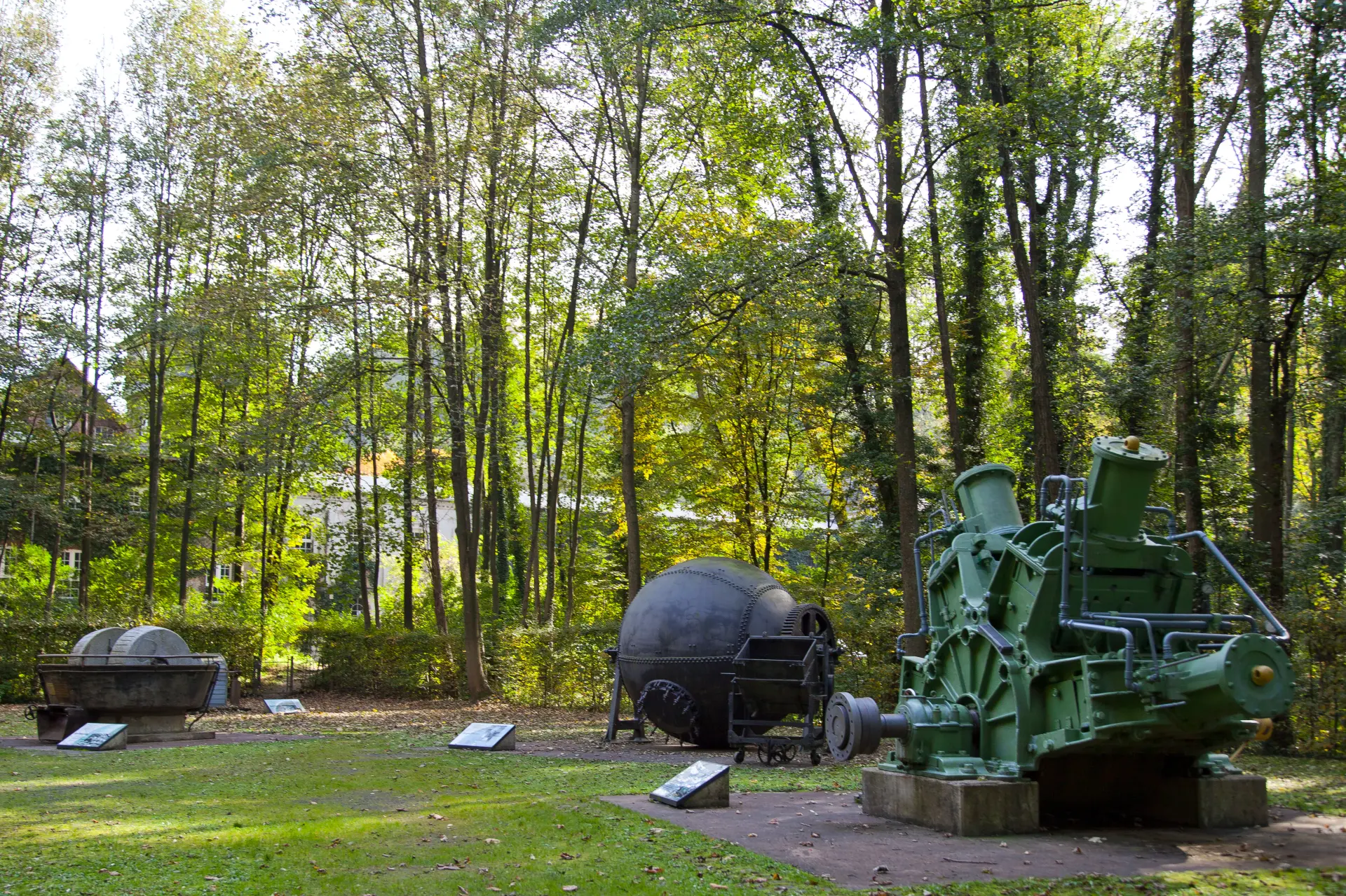 Historische Maschinen mit Infotafeln in einem Park
