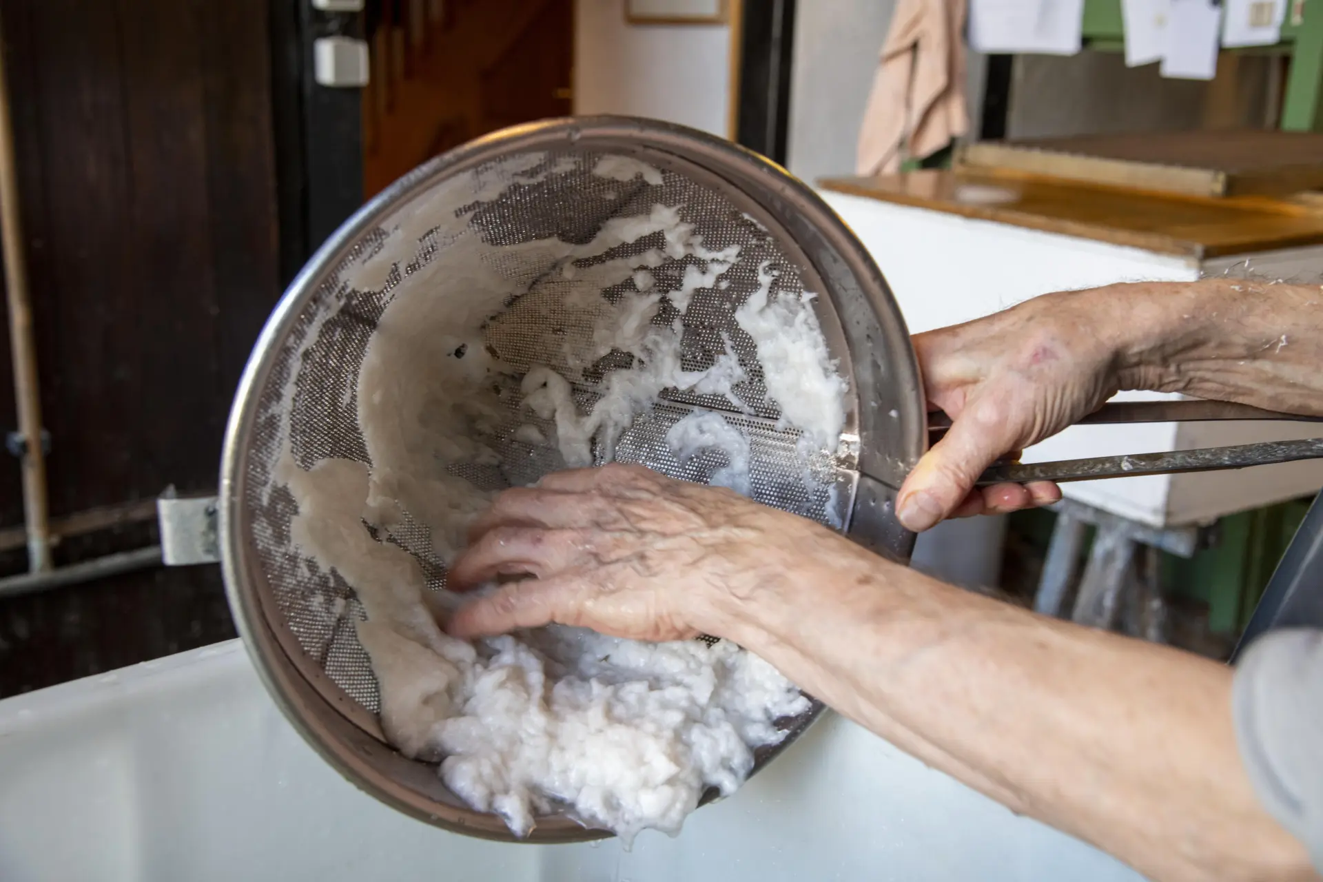 Aufbereitung der Papierfasern: Der Faserbrei wird abgesiebt und von Hand weiterverarbeitet, bevor daraus neue handgeschöpfte Papierbögen entstehen.