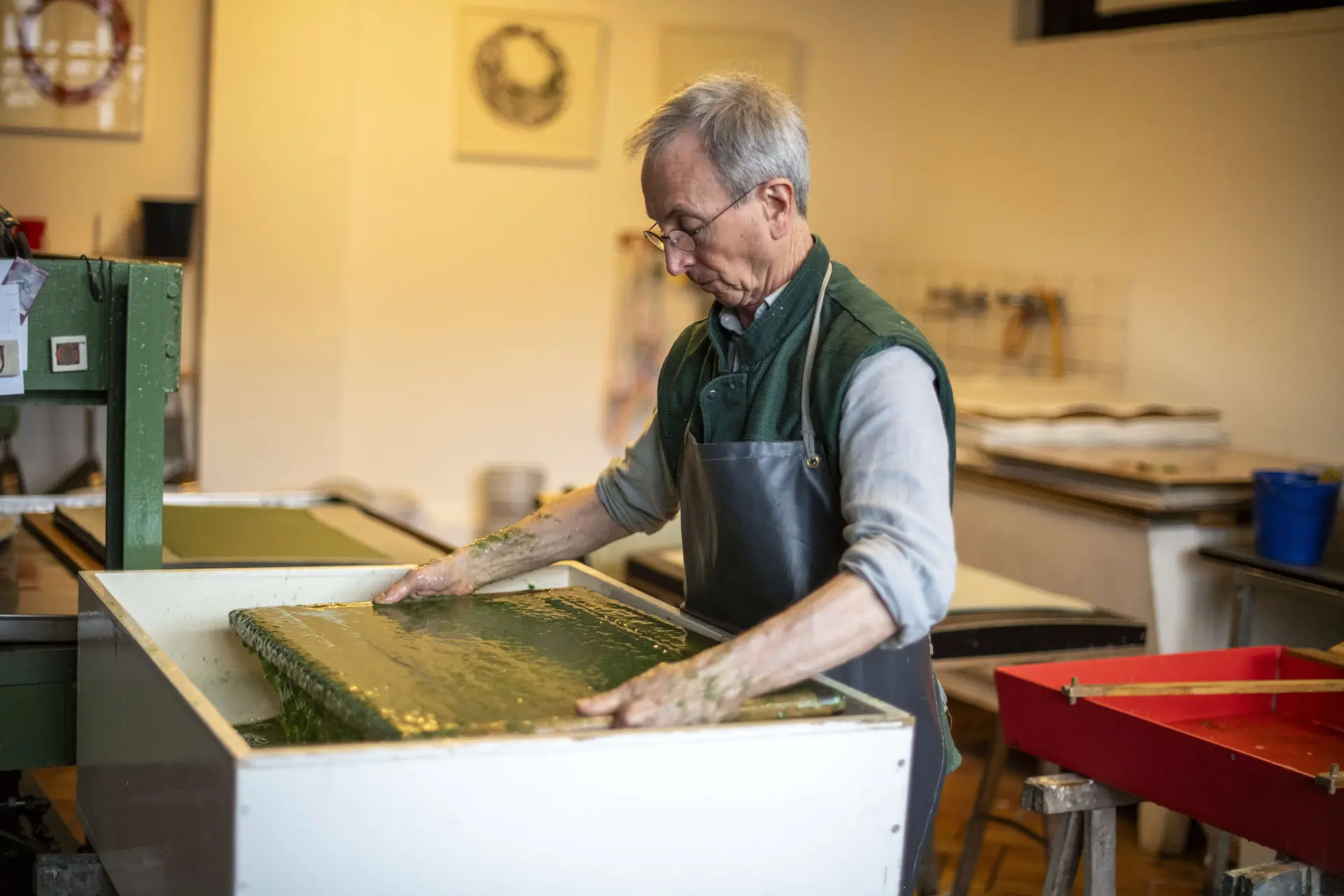 Ein Mann beim Papierschöpfen in seinem Atelier – hier wird aus Fasern, Wasser und Papierbrei ein einzigartiger Papierbogen.