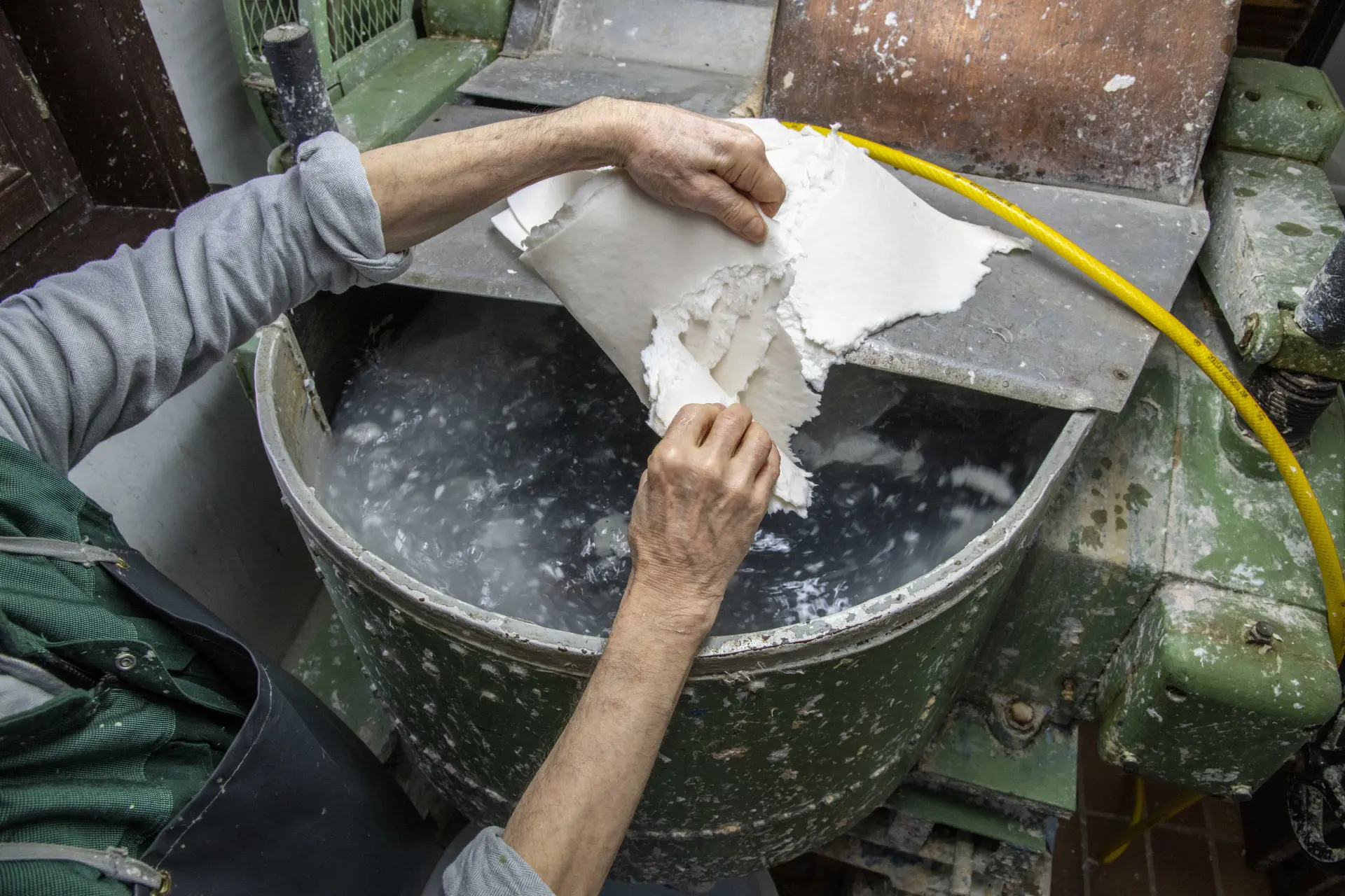 Aufbereitung der Papierfasern: Der Faserbrei wird abgesiebt und von Hand weiterverarbeitet, bevor daraus neue handgeschöpfte Papierbögen entstehen.