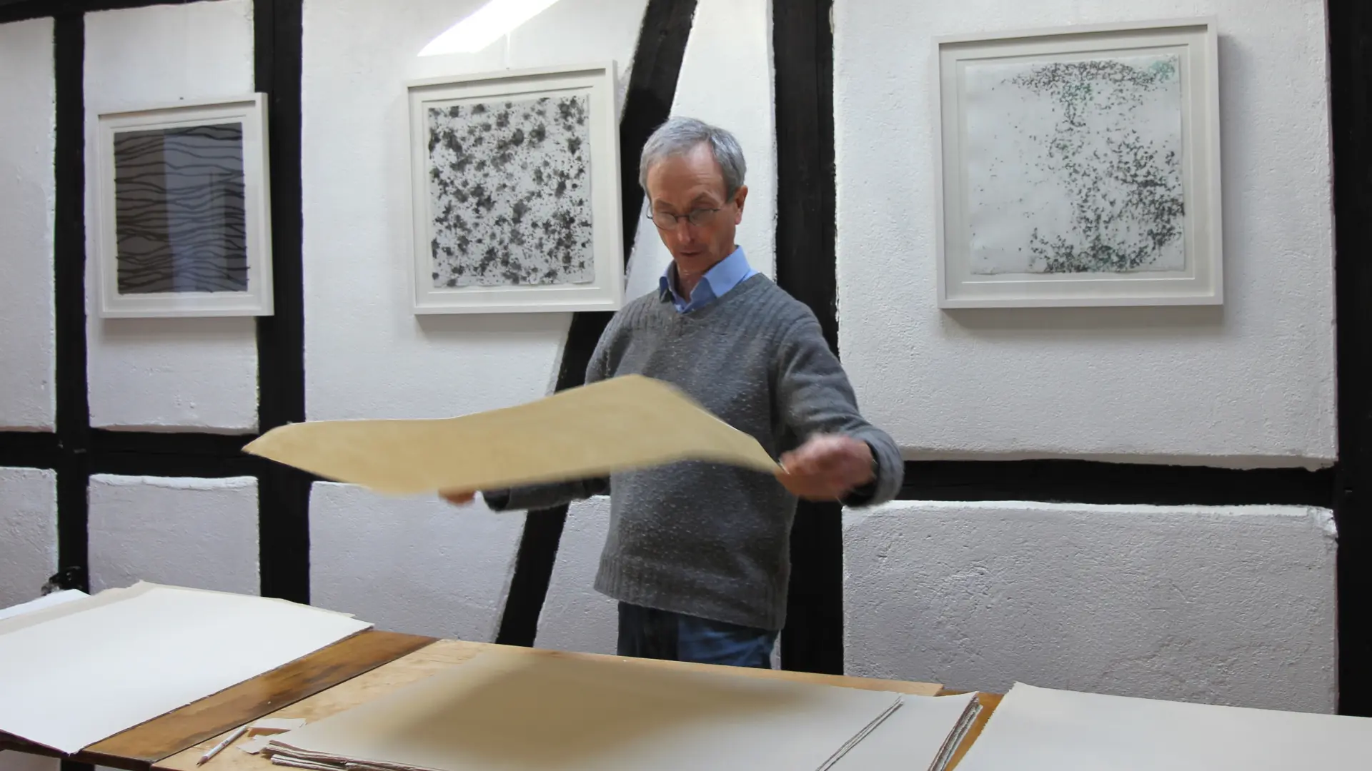 Der Künstler John Gerard sortiert große Bögen Papier.