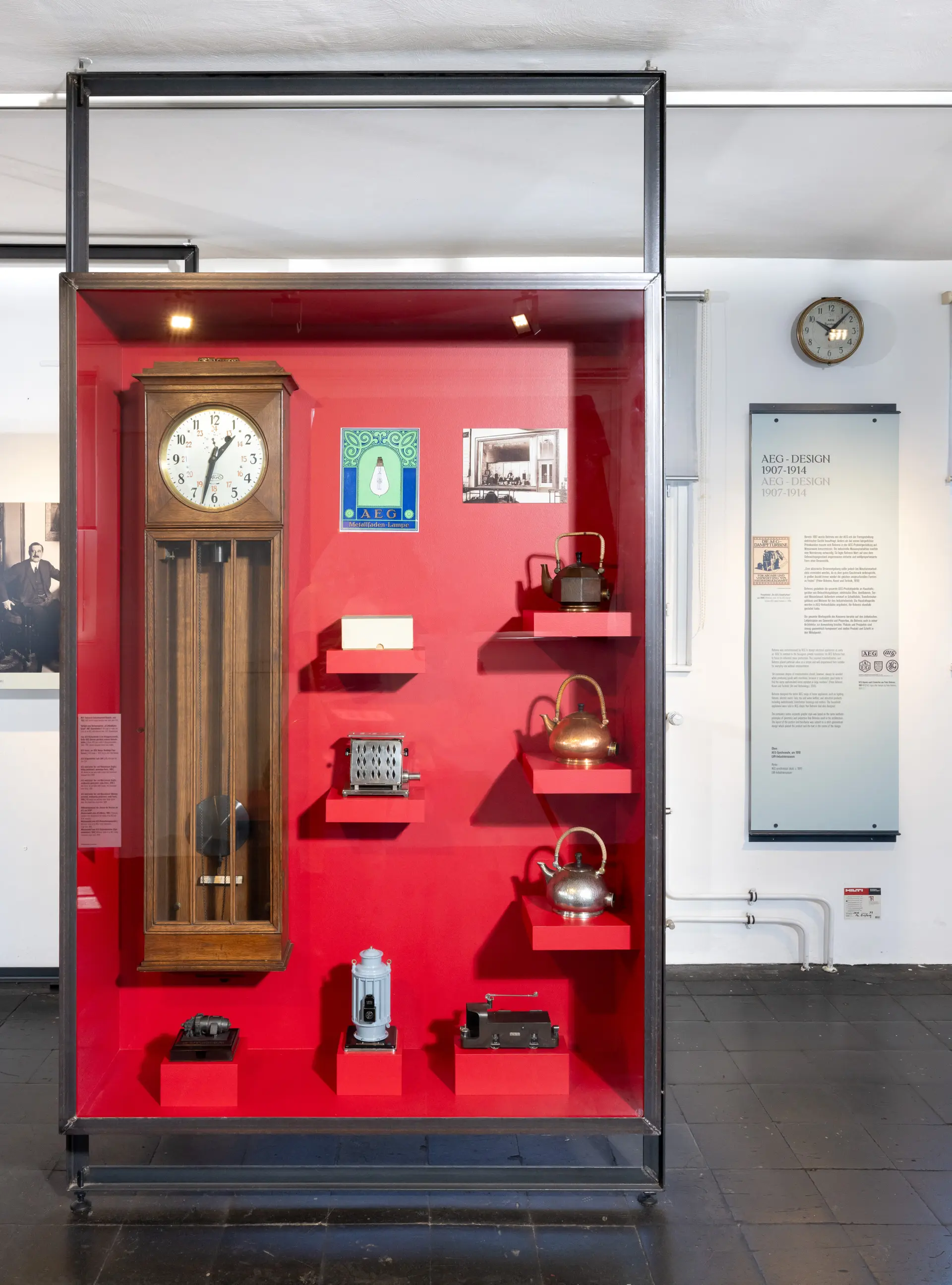 Rote Wand mit verschiedenen Exponaten in einer Ausstellung