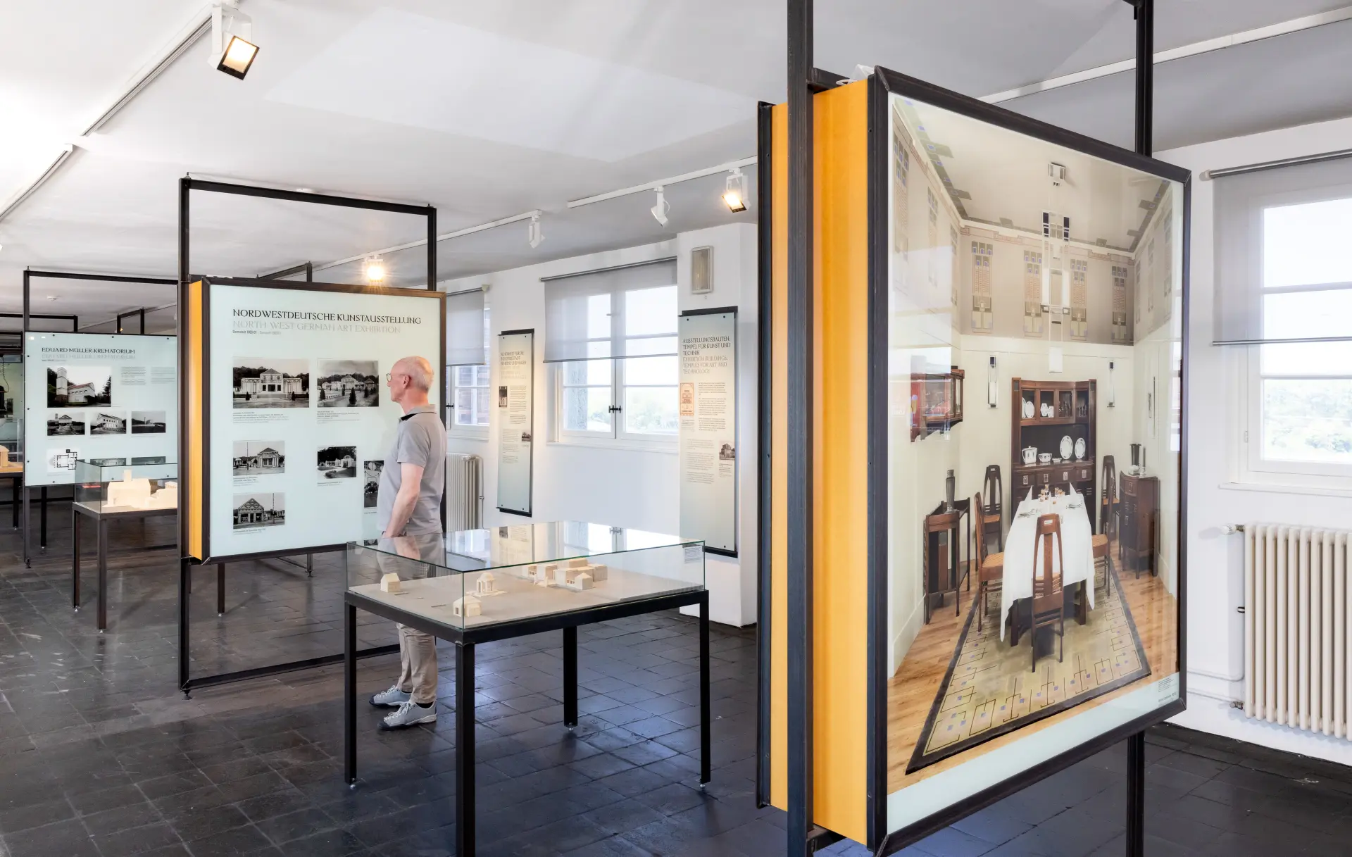 Blick in eine Ausstellung mit Bildwänden und Vitrinen