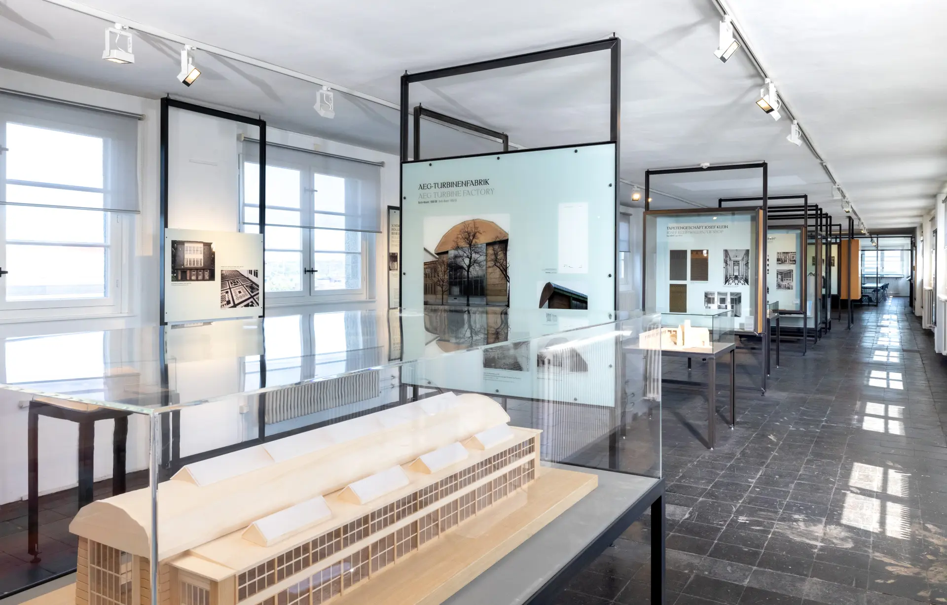 Blick in eine Ausstellung mit einem Modell eines Gebäudes und Bildwänden