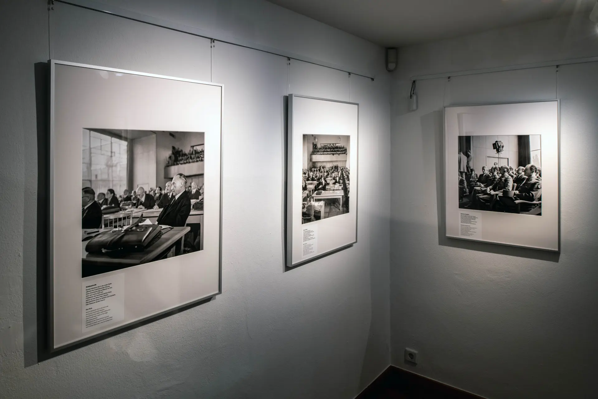 Blick in eine Ausstellung. An der Wand hängen drei historische schwarz-weiss Fotografien.