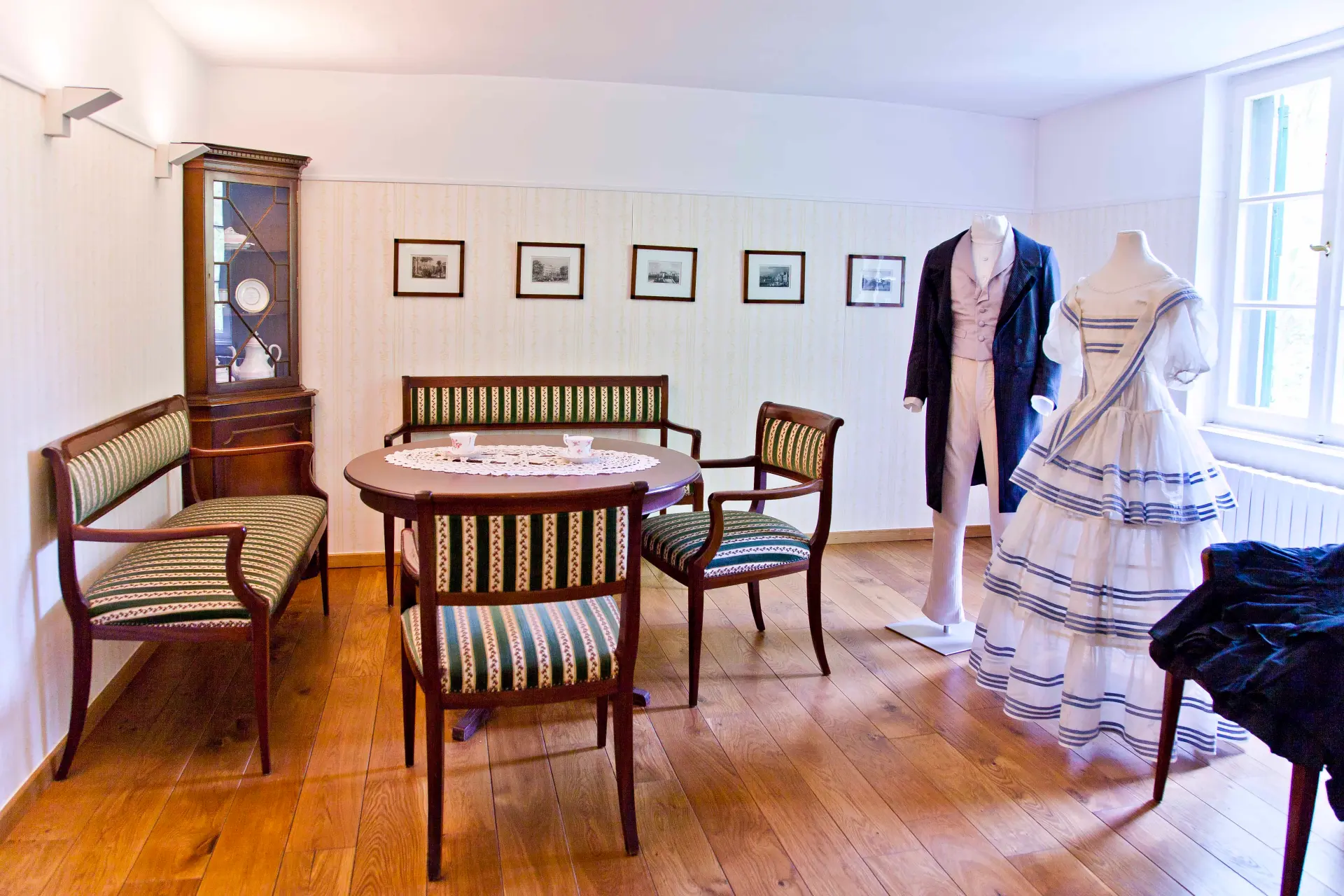 Blick in einen Salon mit historischen Möbeln und historischer Kleidung an Figurinen