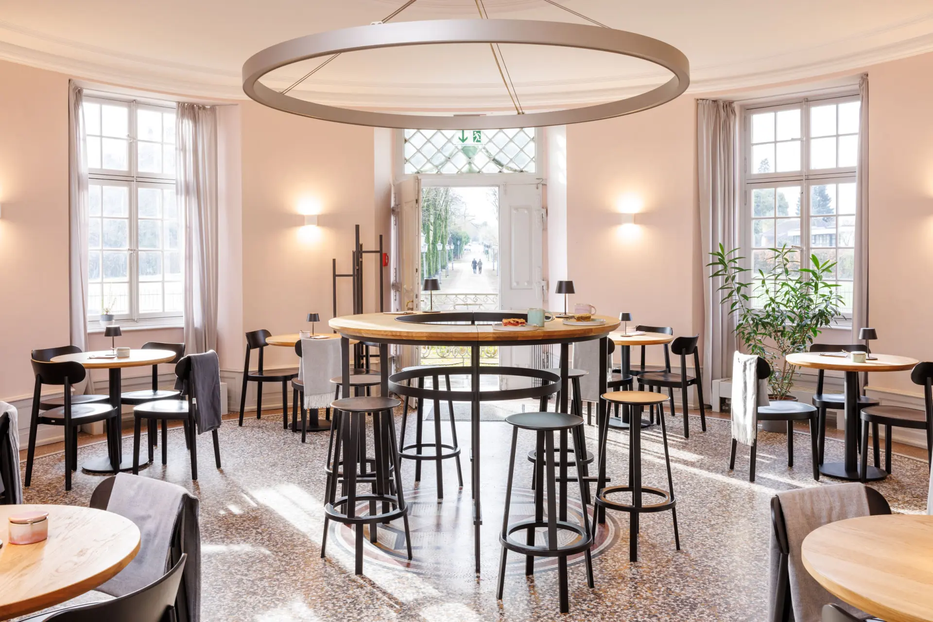 Blick in ein Café mit Stühlen, Tischen und großen Sprossenfenstern