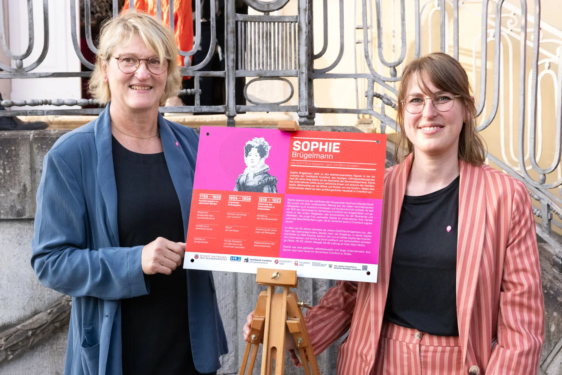 Zwei Frauen halten eine Informationstafel hoch