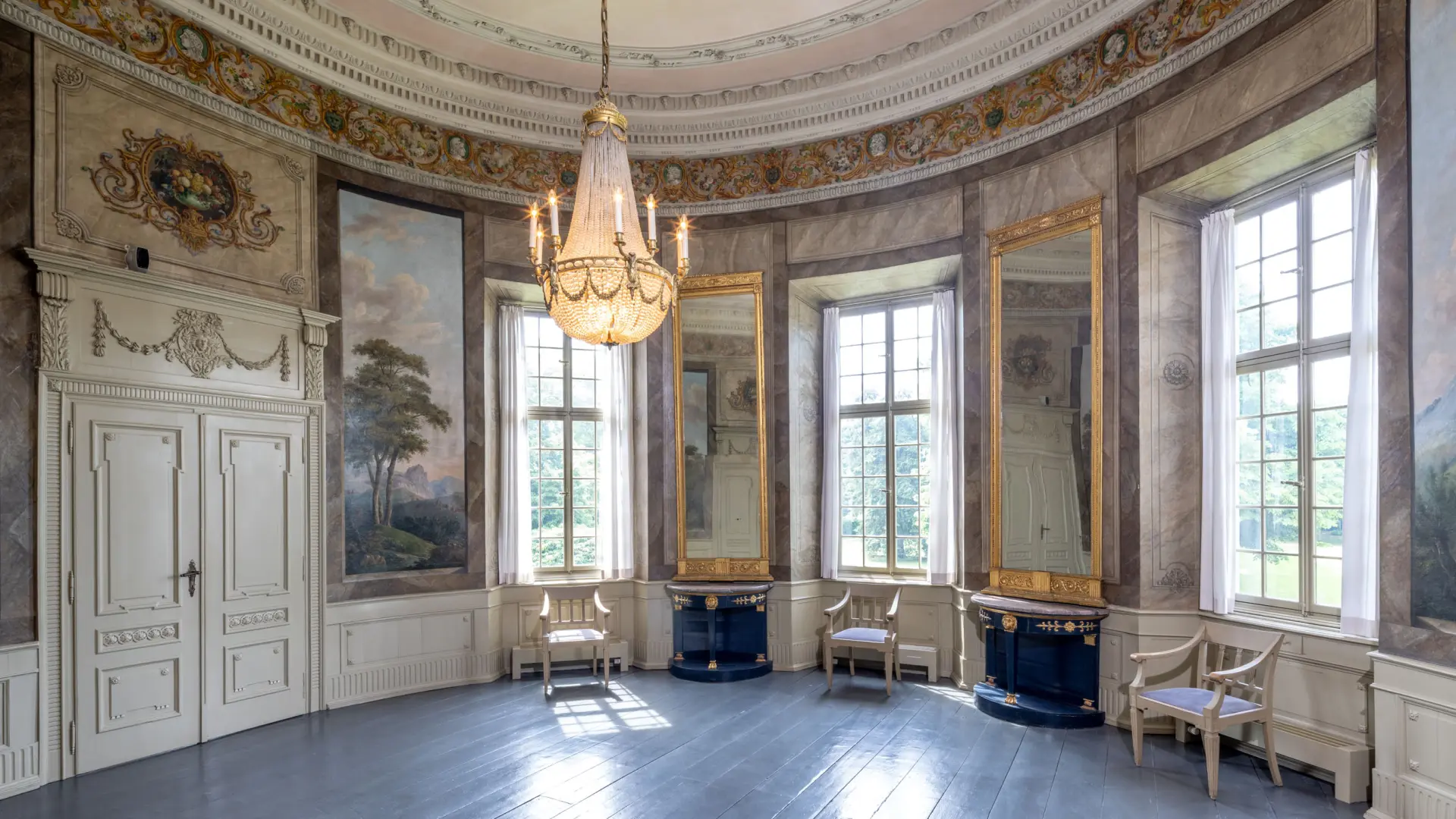 Blick in einen runden Saal mit Landschaftsmalereien an den Wänden