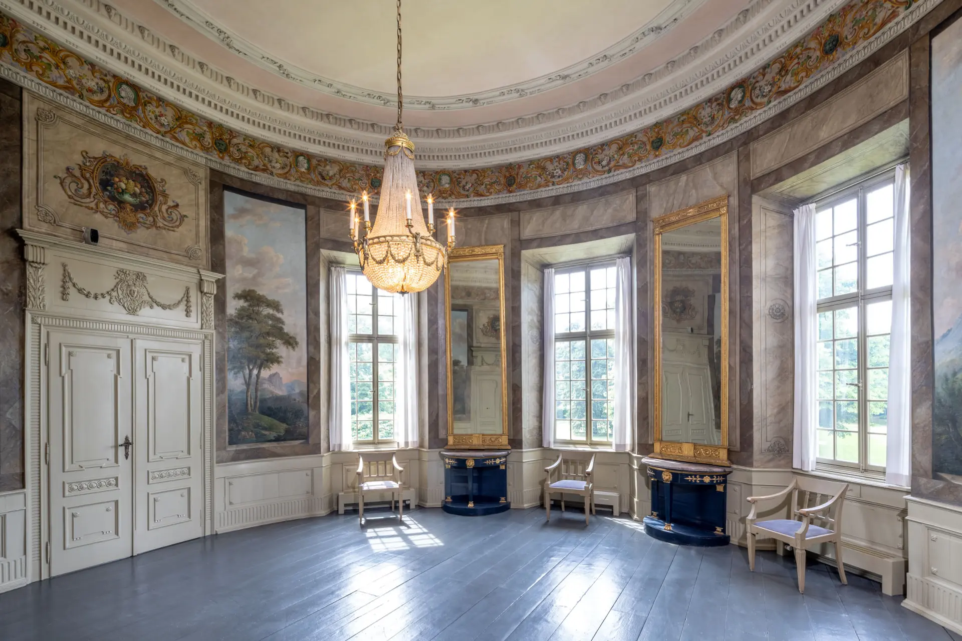 Blick in einen runden Saal mit Landschaftsmalereien an den Wänden