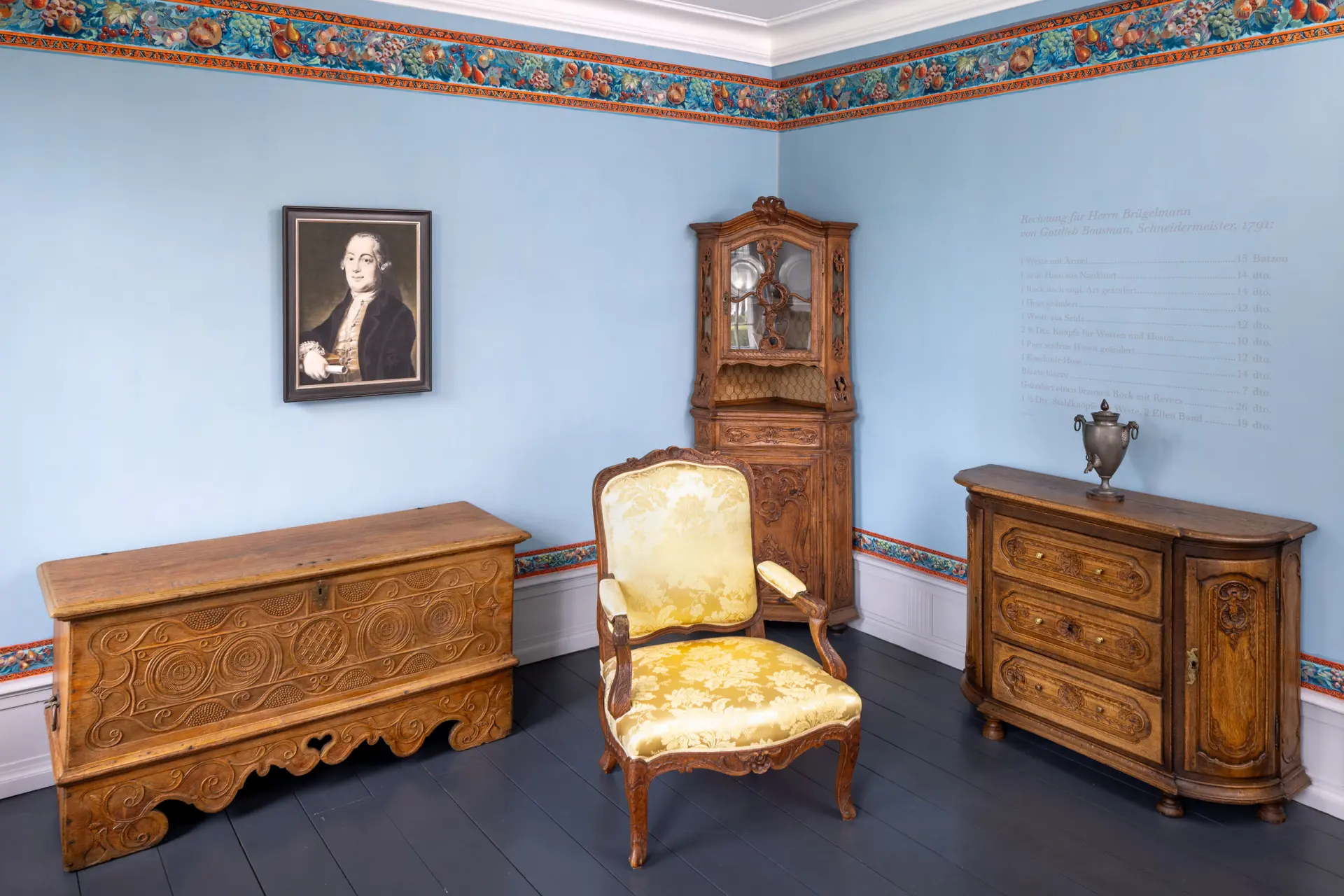 Blick in eine Ausstellung mit historischen Möbeln und Wandportait