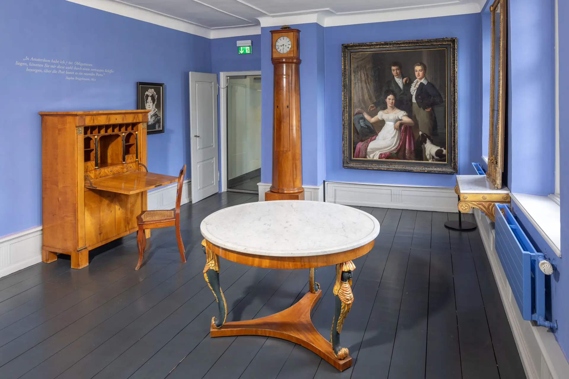 Blick in eine Ausstellung mit historischen Möbeln und Gemälde an der Wand