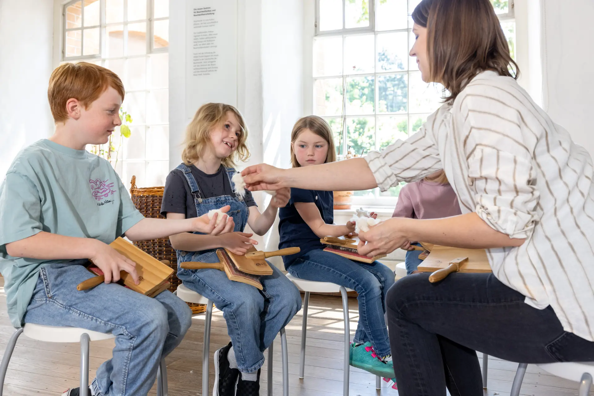 Drei Kinder und eine Museumspädagogin bearbeiten rohe Baumwolle