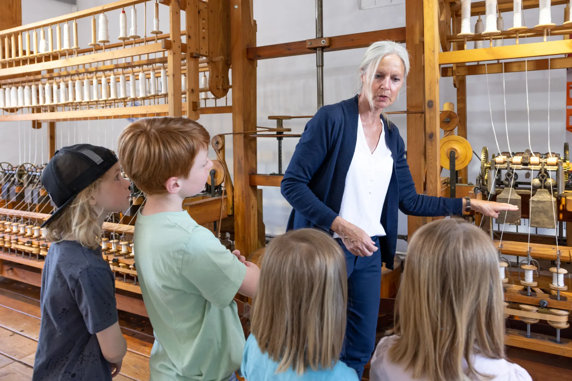 Eine Kindergruppe mit Museumsgästeführerin vor einer großen Spinnmaschine