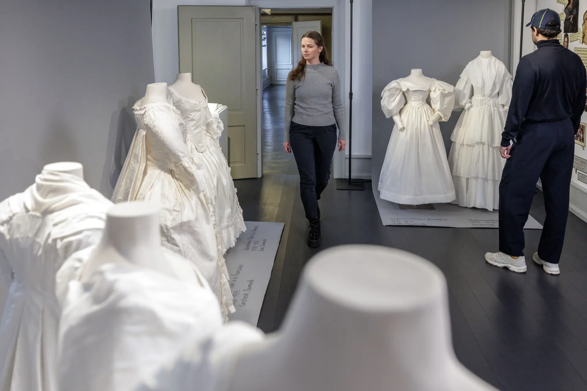 Ein Mann und eine Frau in einem Ausstellungsraum mit weißen Kleidern an Figurinen