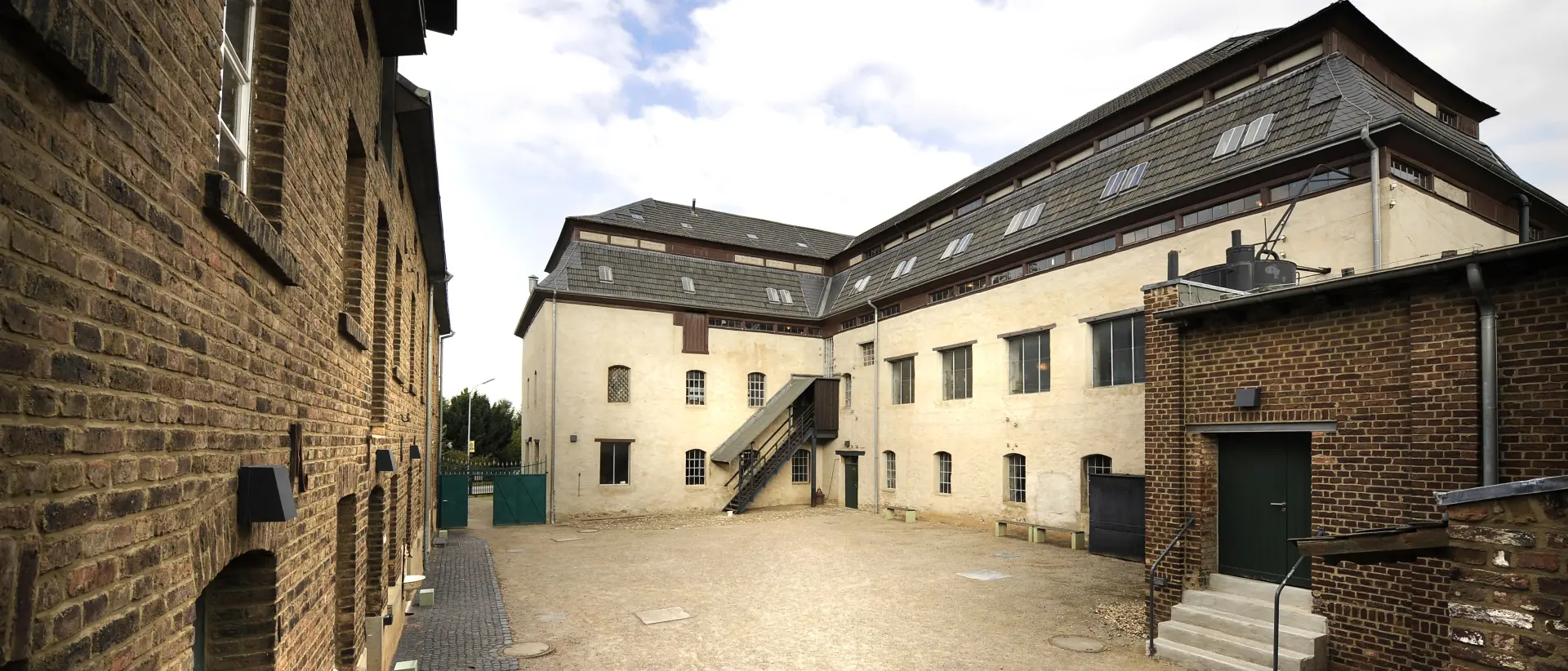 Blick in einen Fabrikhof mit umliegenden Gebäuden