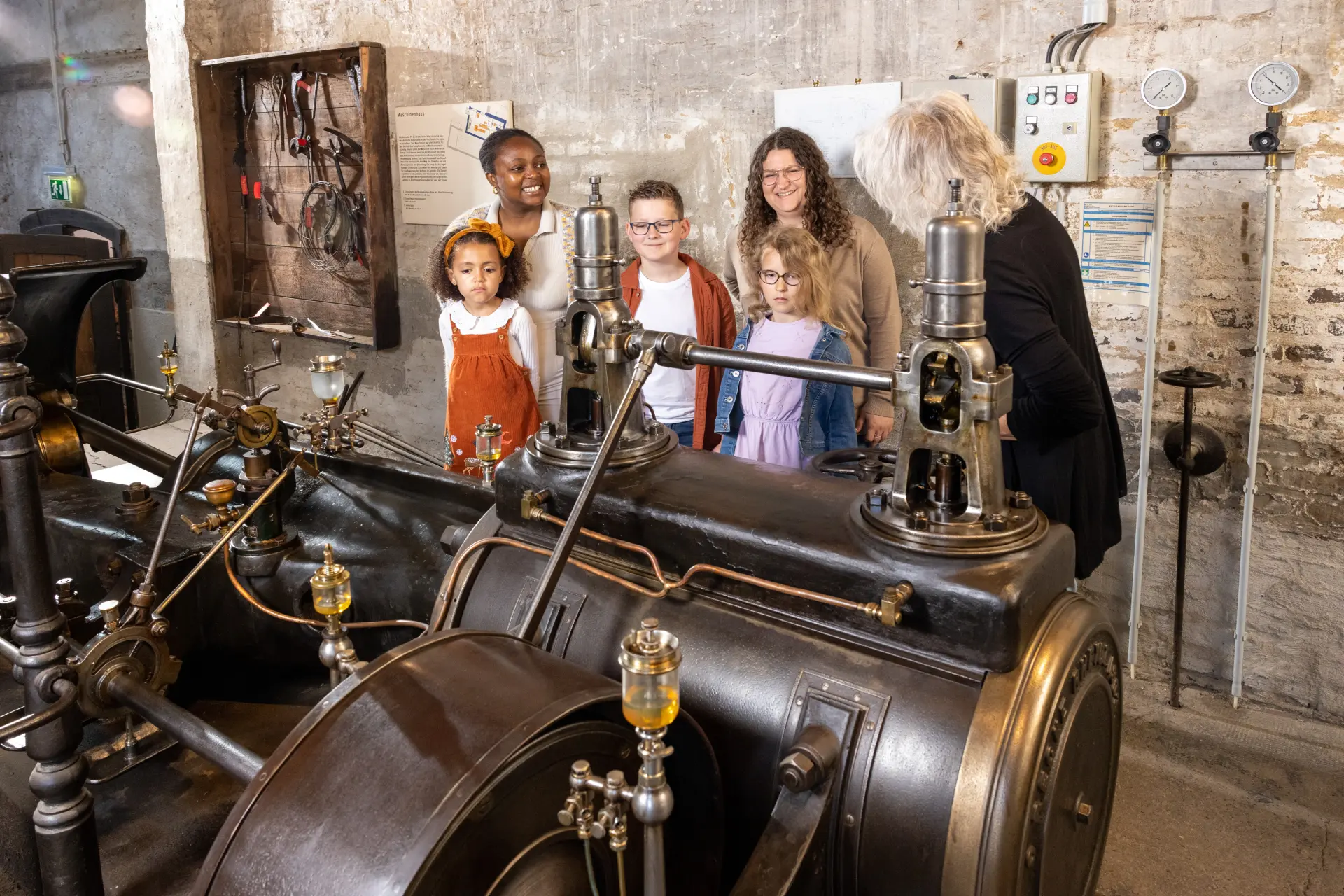 Eine geführte Gruppe sieht sich eine Dampfmaschine an.