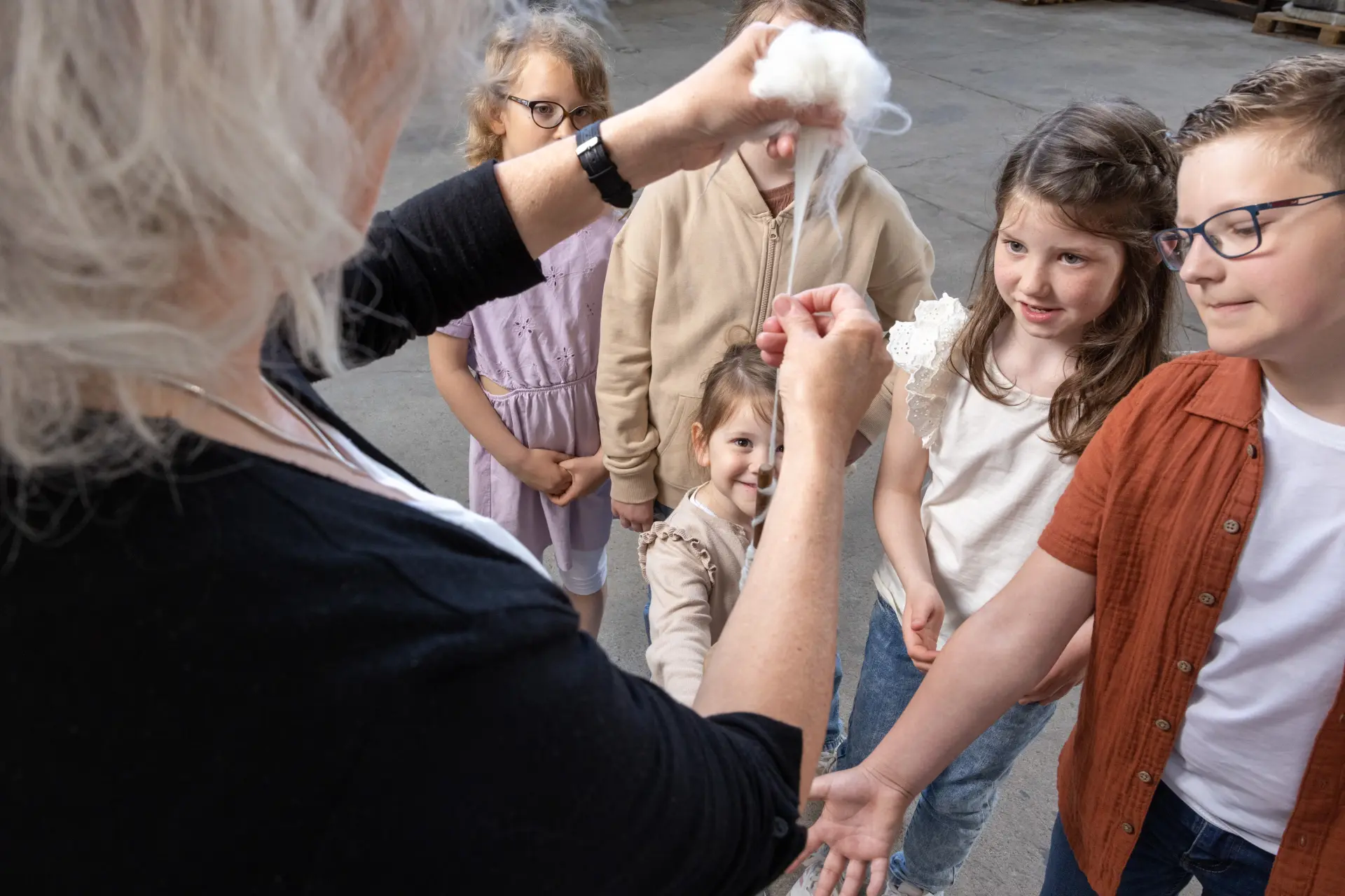 Eine Gästeführerin lässt eine Gruppe von Kindern Wolle berühren.