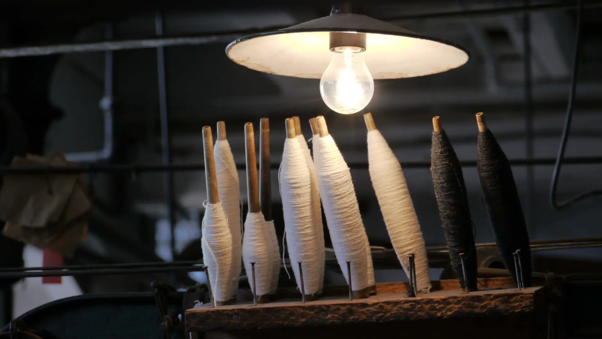 Von einer Lampe beschienene Spulen mit weißem Garn.